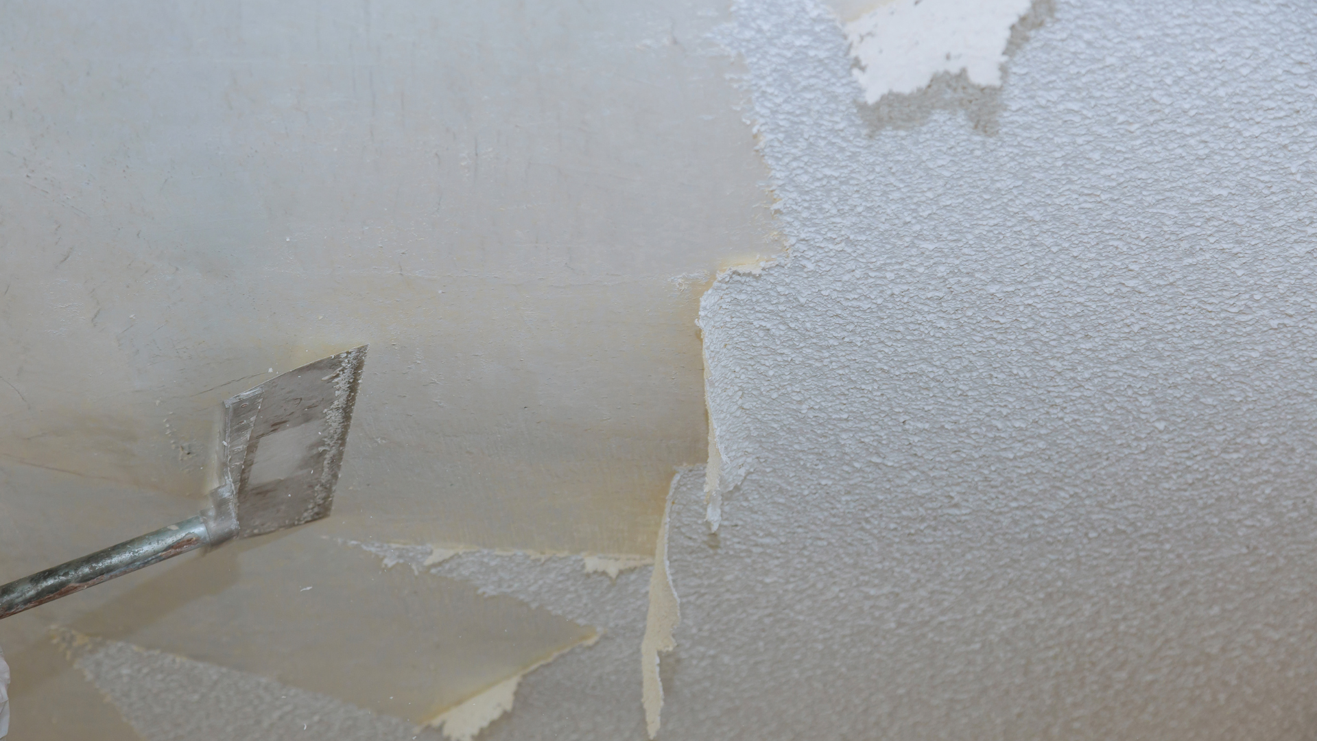 Contractor using a tool to remove popcorn ceiling