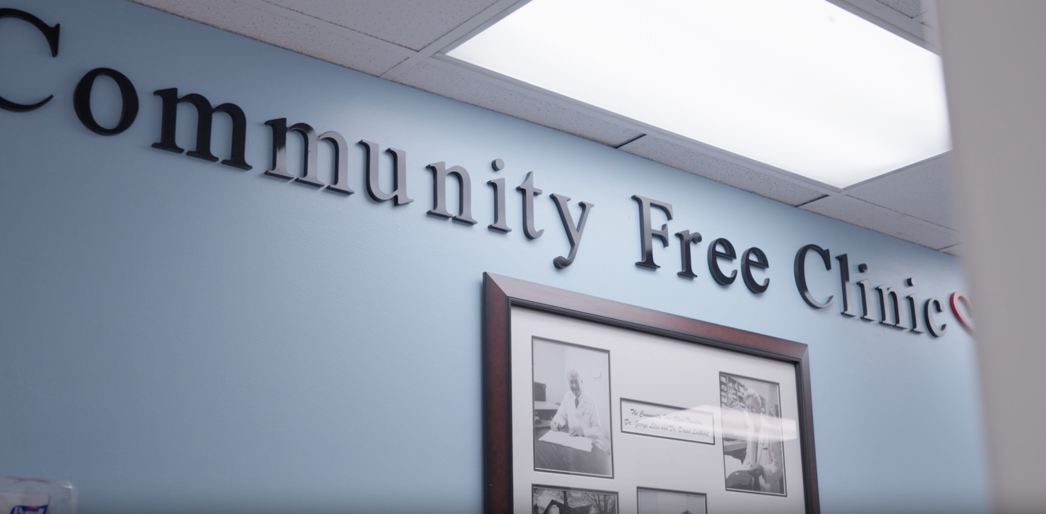 Sign reading 'Community Free Clinic' on a light blue wall.