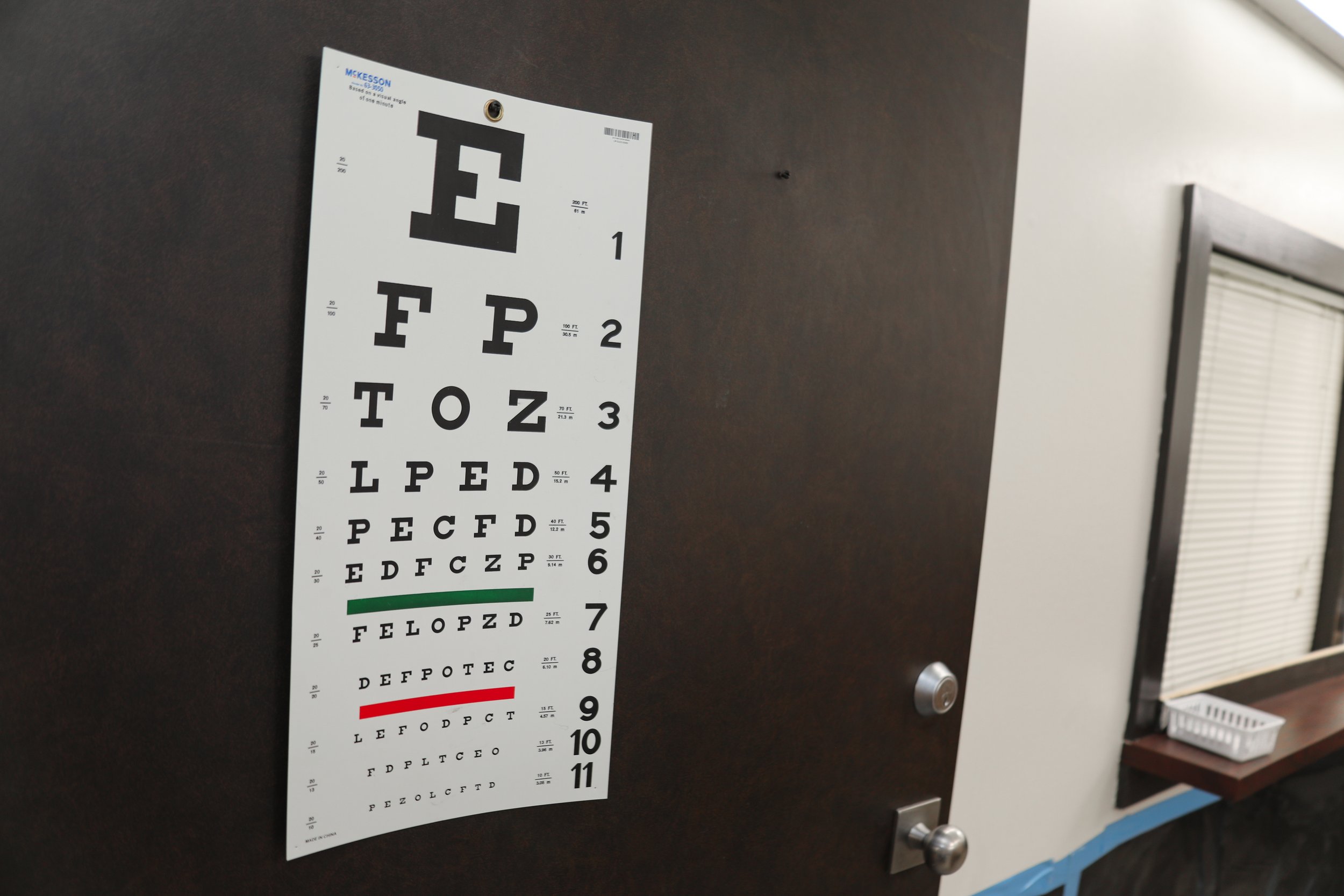 Eye chart on a door with rows of large to small black letters, showing test sizes and distance measurements.