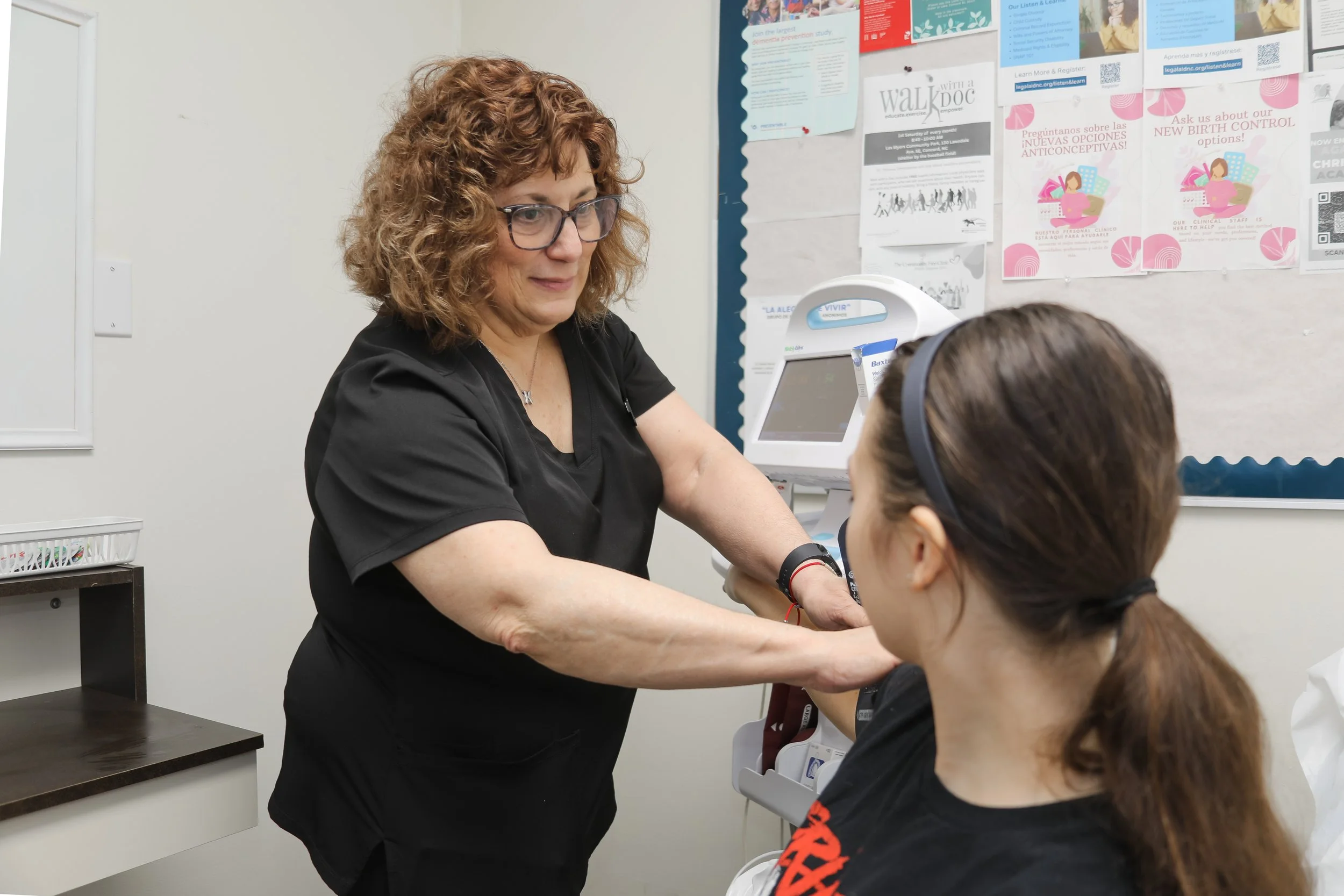 A healthcare professional preparing to take a patient's blood pressure using a blood pressure cuff in a medical office.