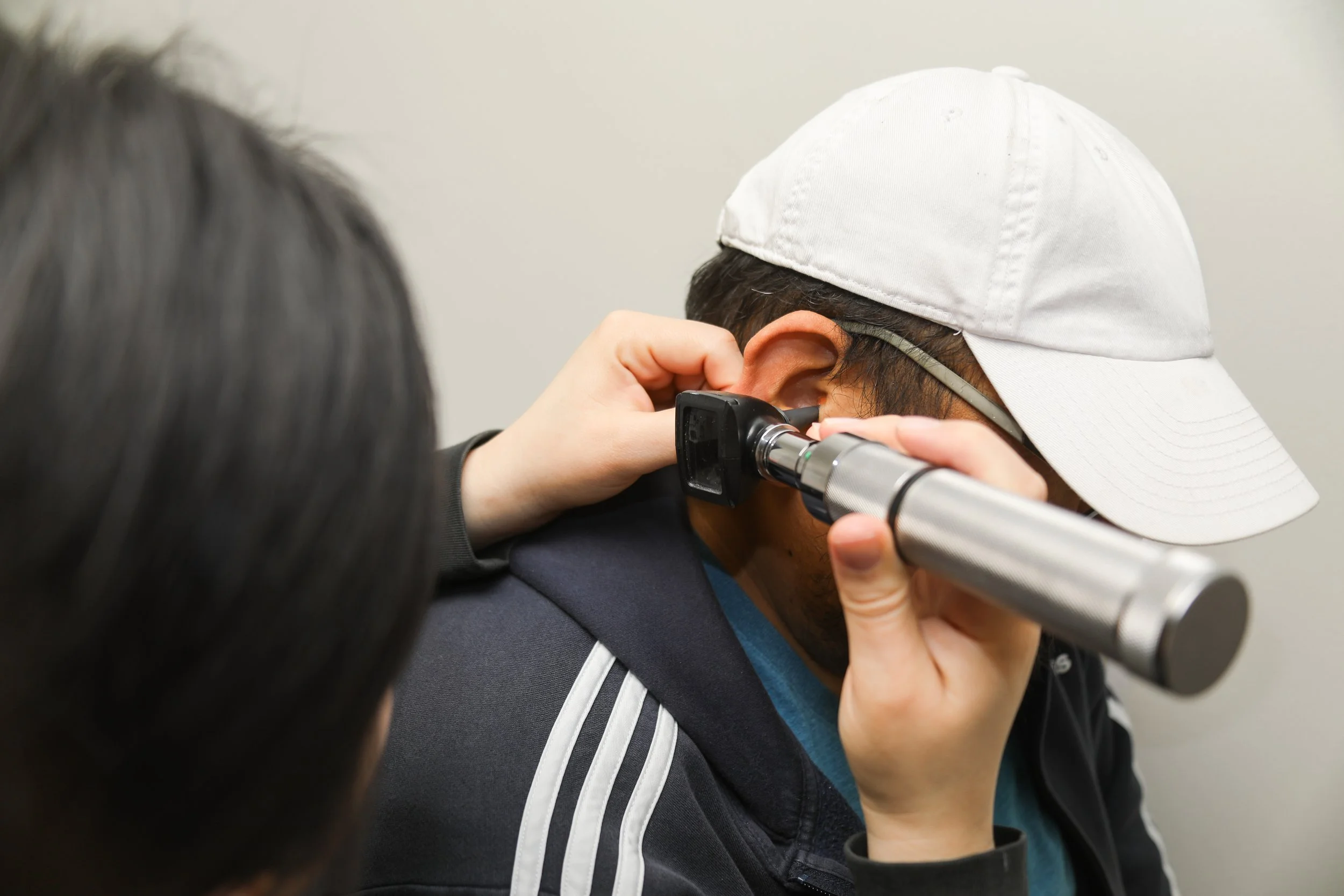 Doctor examining a man's ear with an otoscope.