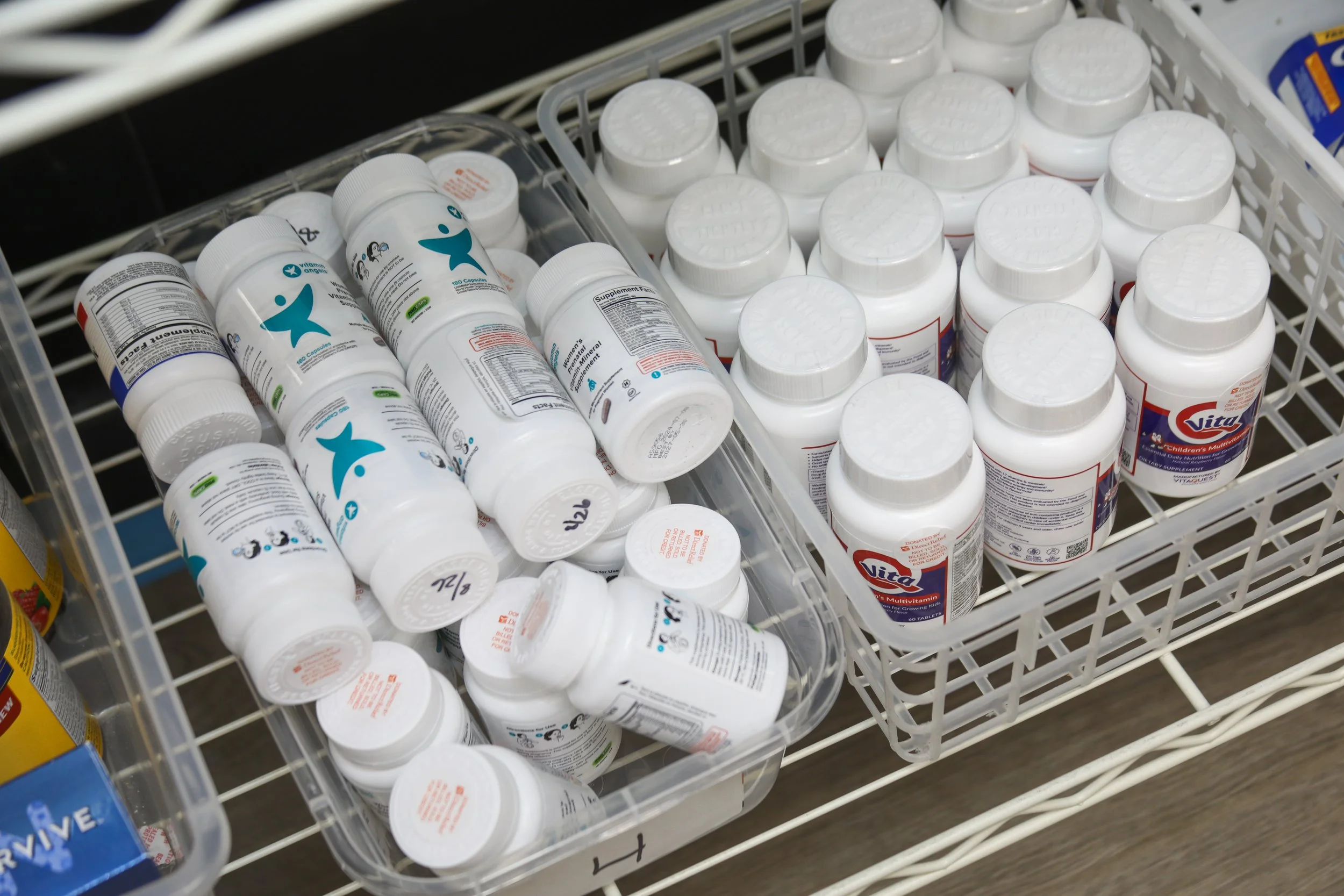 Multiple bottles of dietary supplements or vitamins stored in plastic bins on a store shelf.