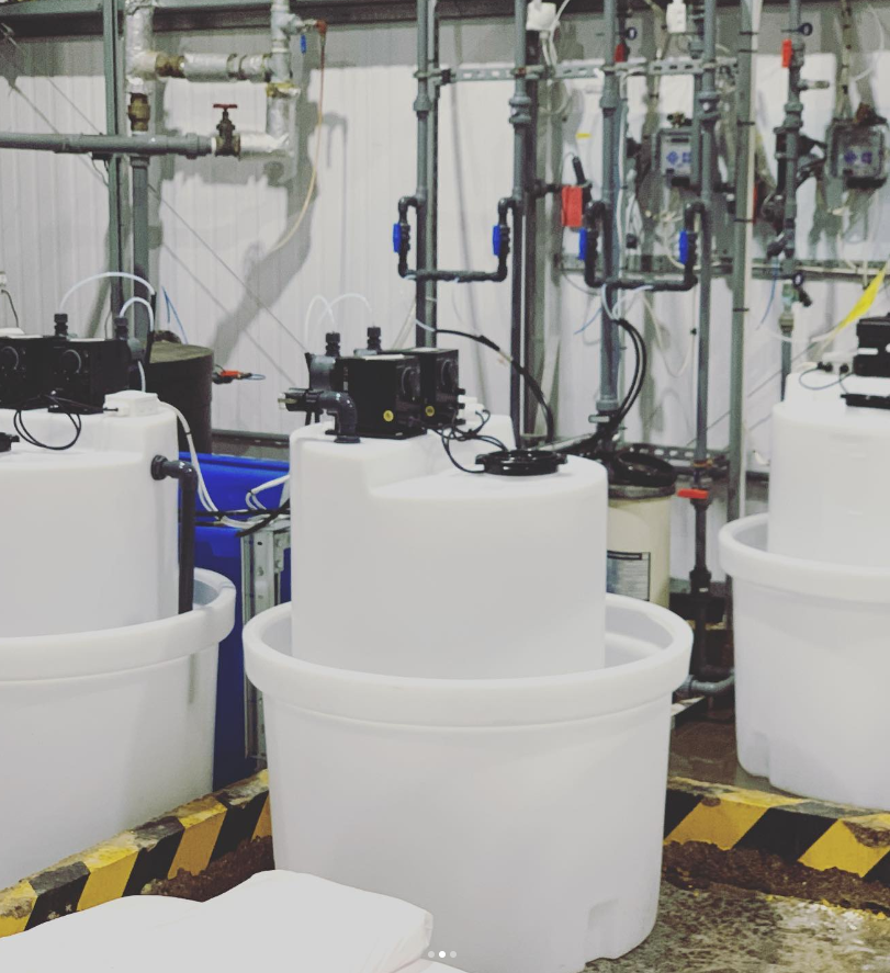 Industrial water testing equipment with tanks, pipes, and gauges in a laboratory setting.