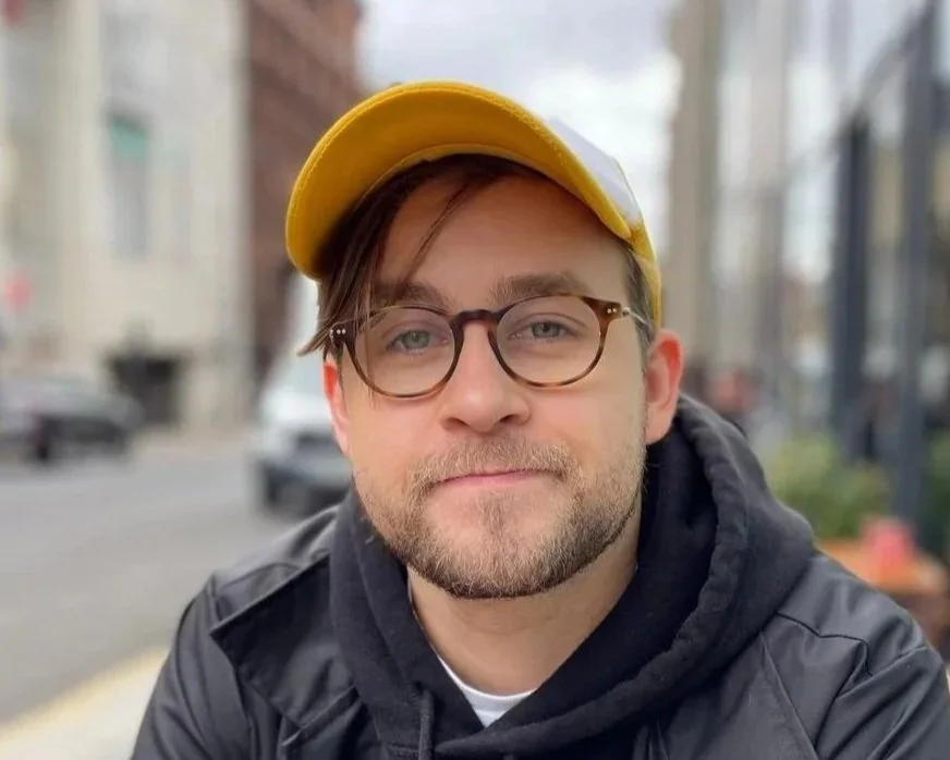 A man with glasses smiling at the camera.
