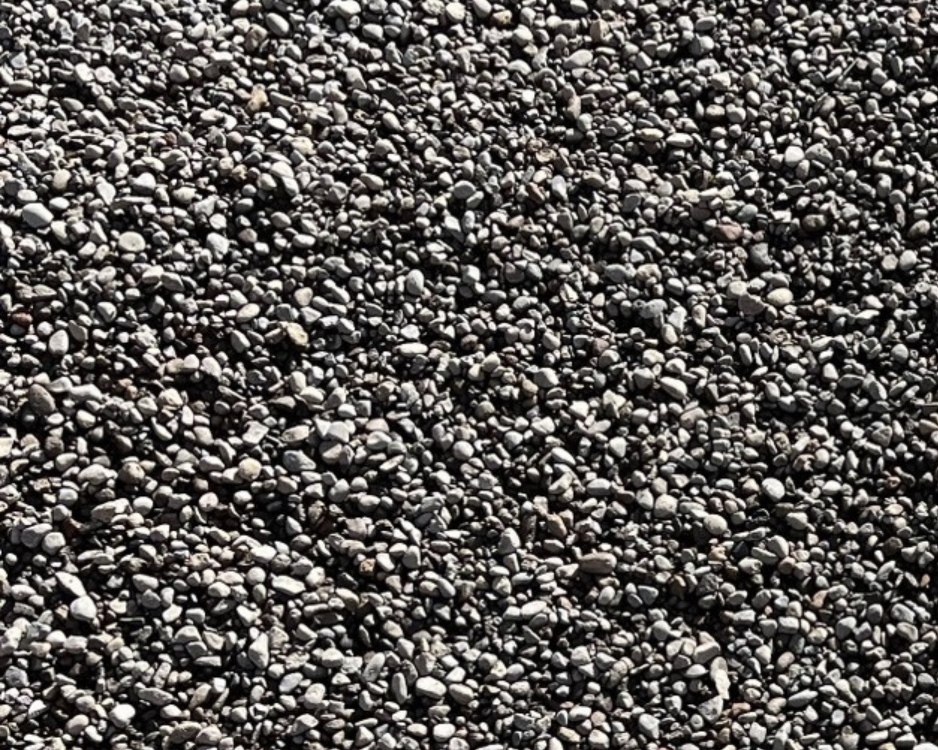 Close-up of small, smooth, grey and black pebbles scattered on a surface.