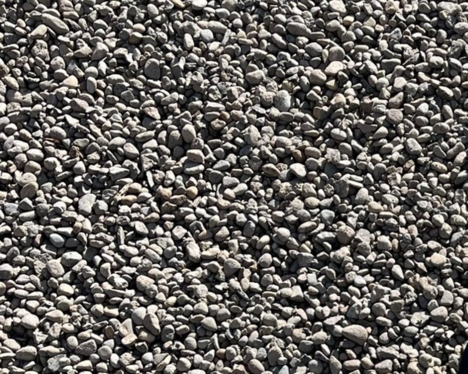Close-up of a surface covered with small, rounded gray and tan pebbles.