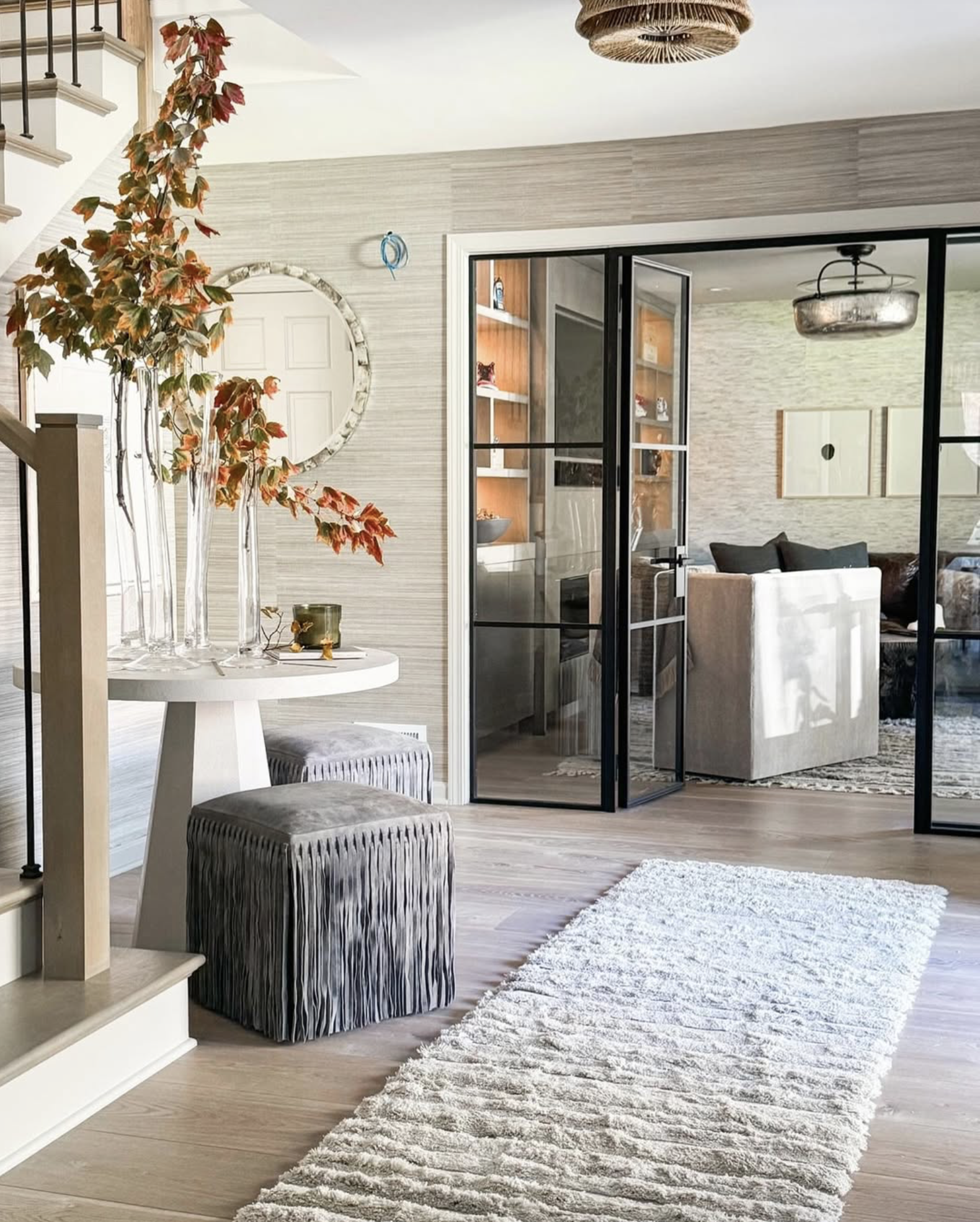 Living room with glass sliding doors, a beige sofa, wall art, and a textured area rug.