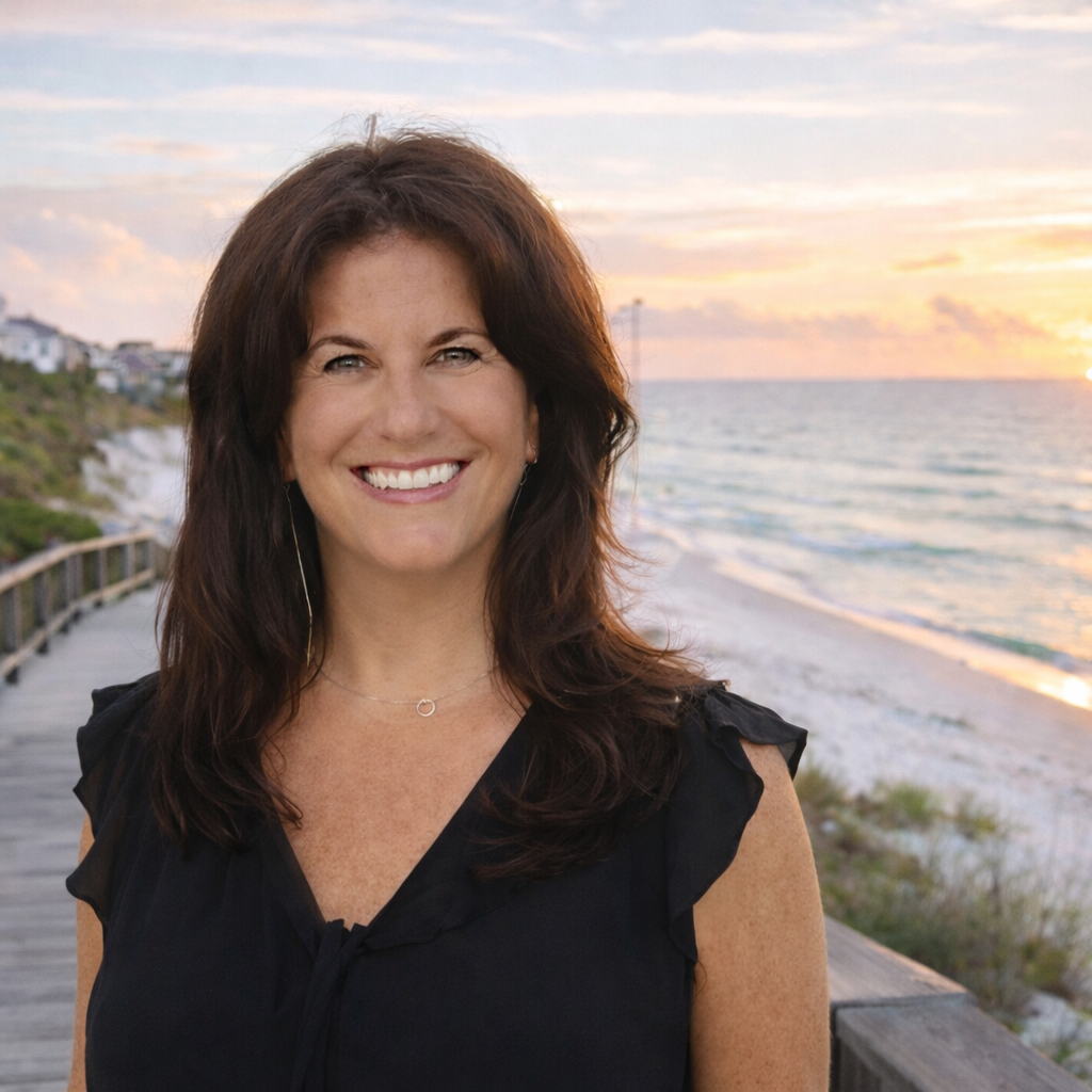 Ashley Grant, interior designer, smiling at the camera on a beach boardwalk during sunset.
