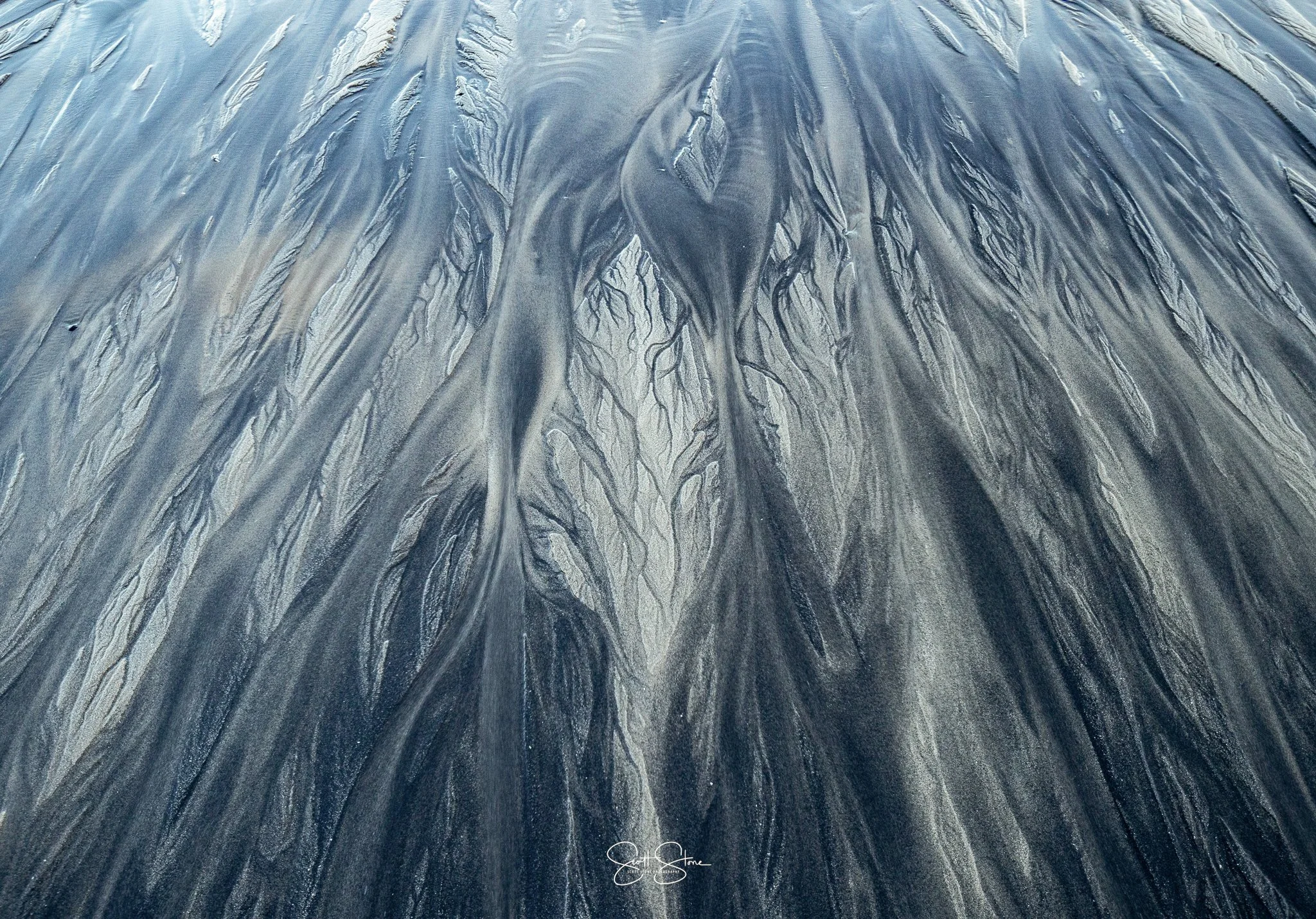 Close-up view of a dark surface with intricate, branching patterns resembling melting or flowing material.