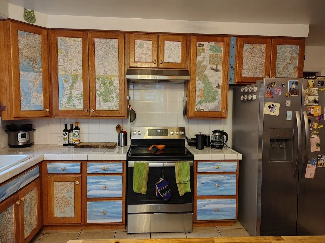 Map art cabinets in kitchen with stove and refrigerator 