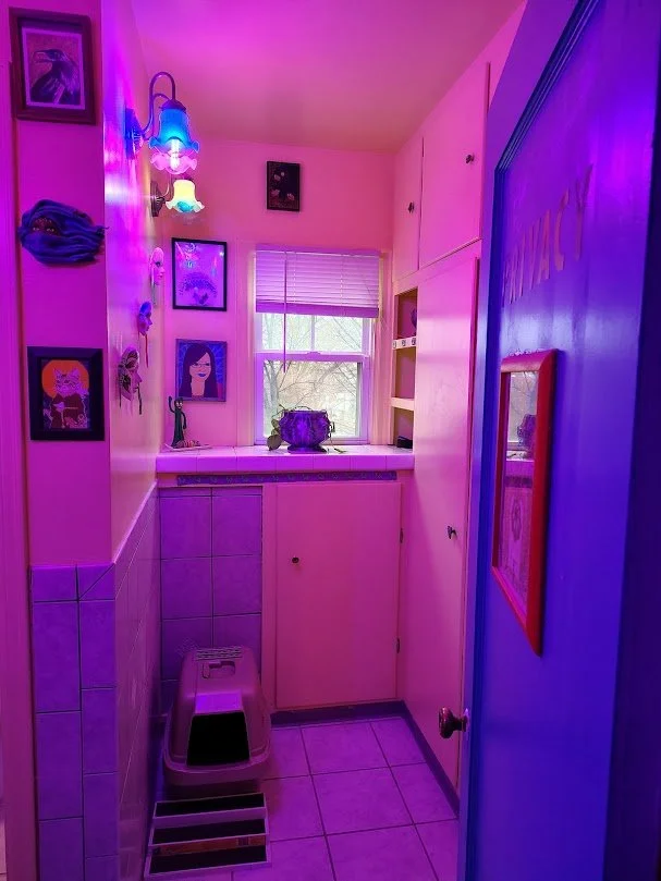 Small red lit room wiith picture frames on wall