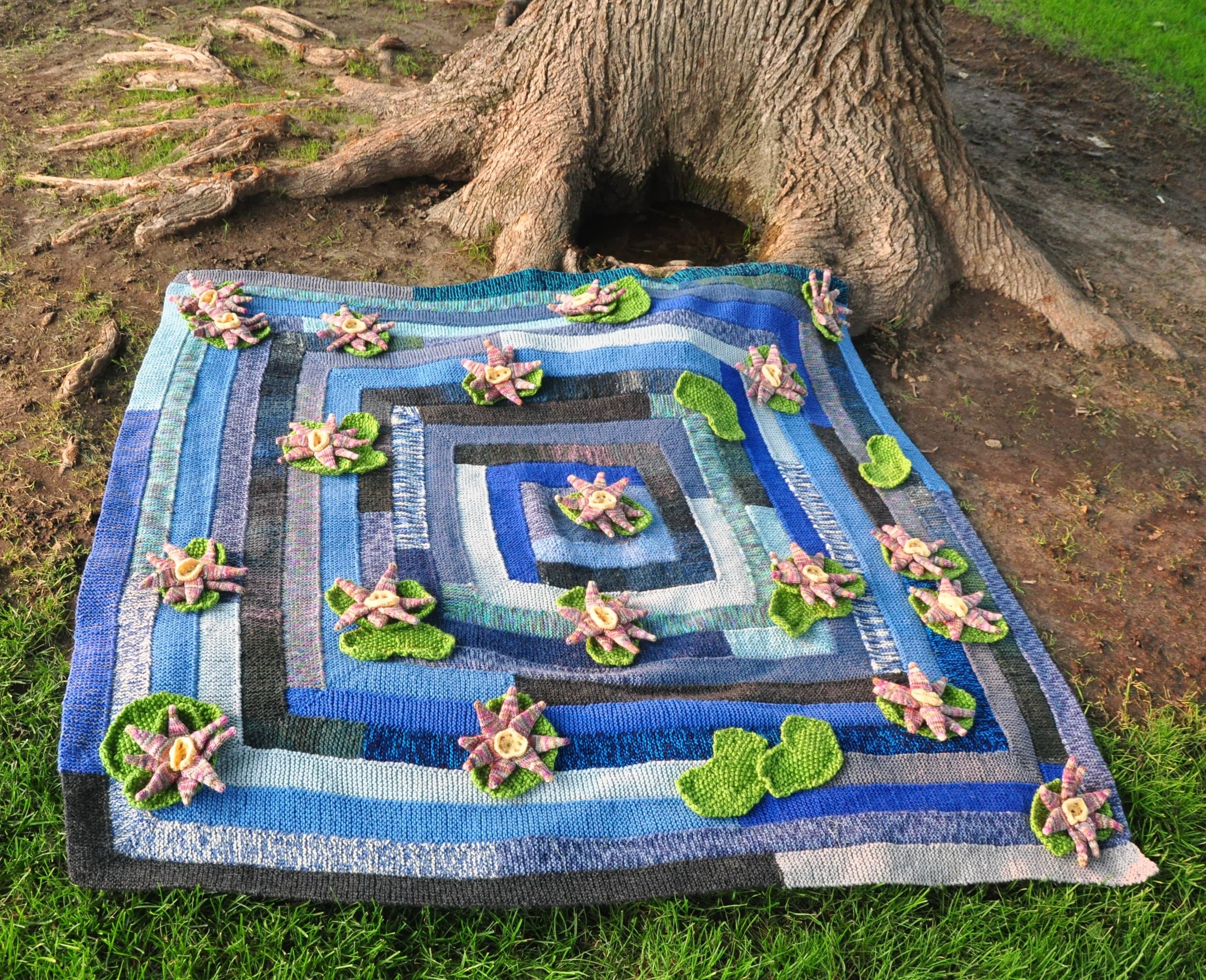 Blue square quilt with pink and green lily pad flowers
