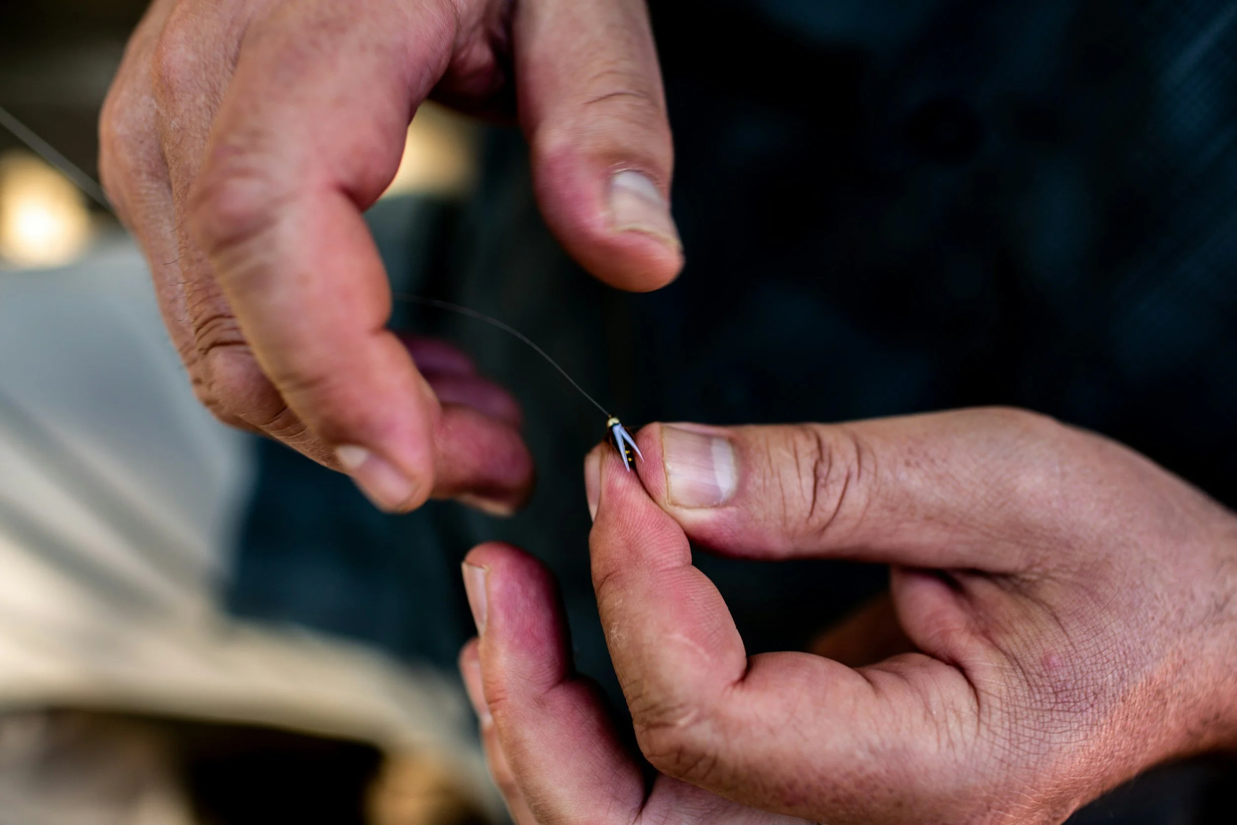Close-up of hands fishing, holding a fishing hook with a fishing line.