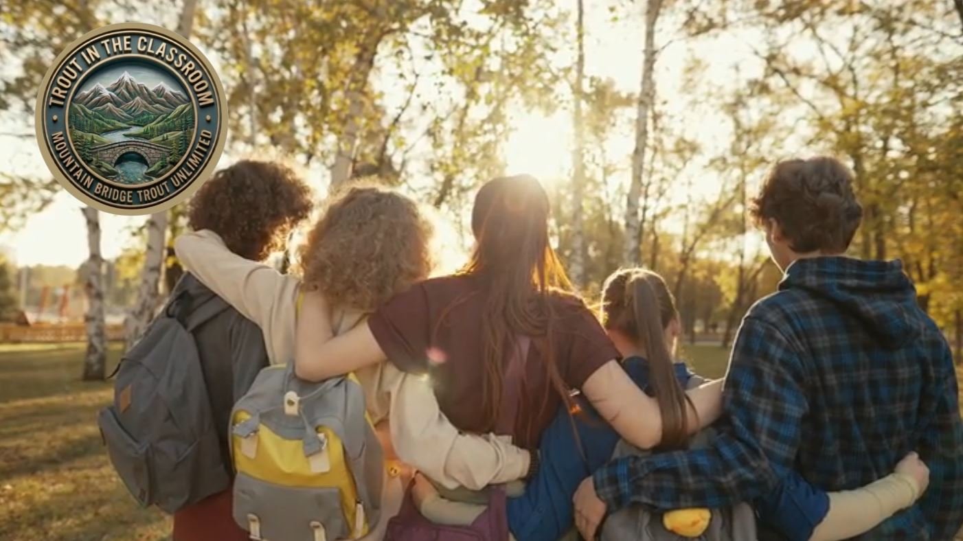 Group of children hugging each other outdoors during sunset in a park with trees in the background.