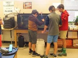 Three children working together on a science experiment at a classroom desk