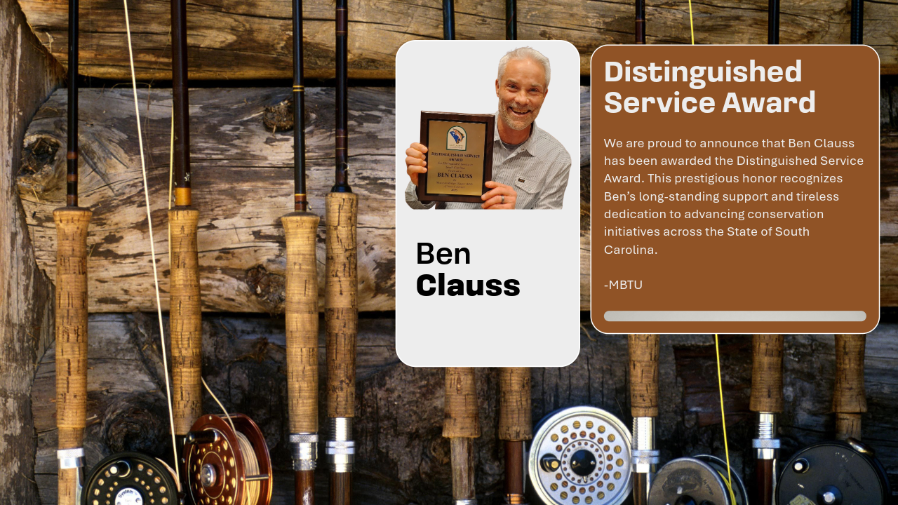 A man holding an award plaque stands in front of a rustic wooden background with fishing rods displayed vertically behind him. The award signifies recognition for distinguished service.