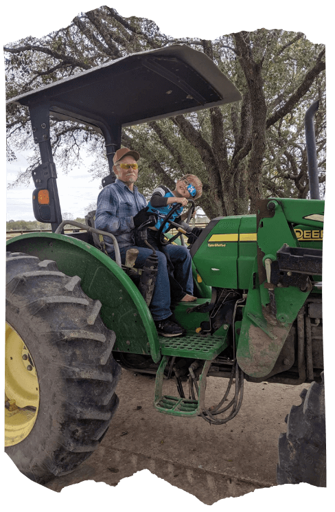 Julius Stuart with his grandson riding a tractor on the Stuart Ranch.