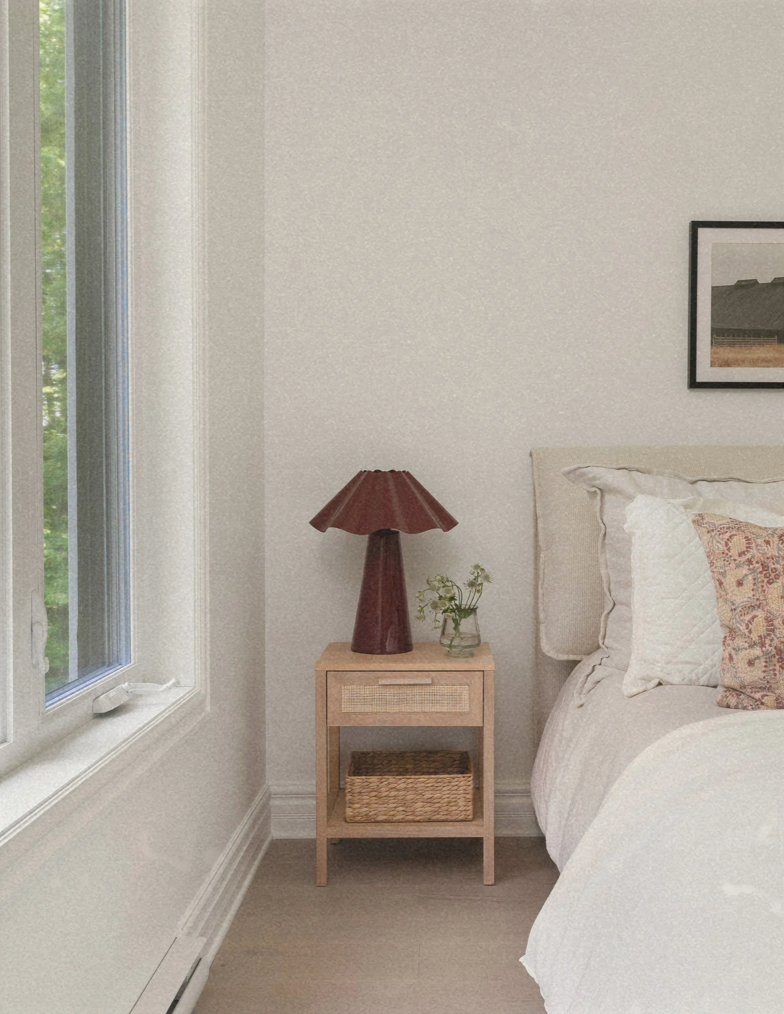 Chambre à coucher apaisante aménagée par Studio Lagom au Lac-Brome, mettant en vedette une lampe de chevet aux tons bourgognes et une table de nuit en bois et cannage.