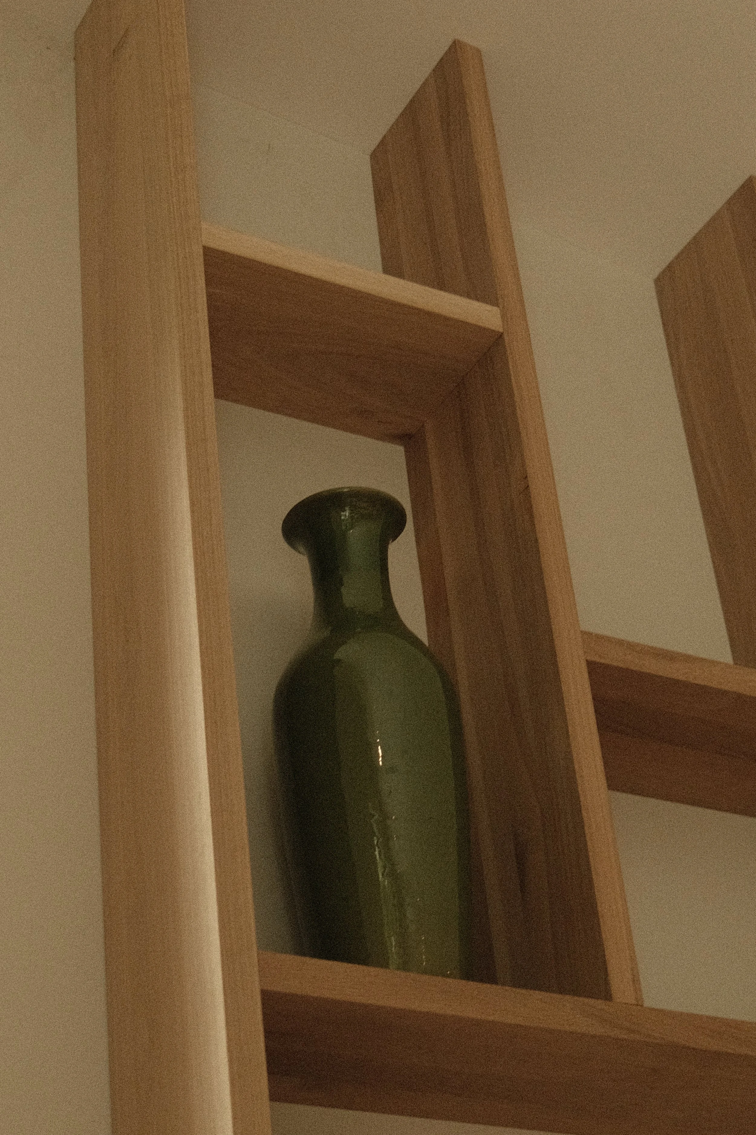 Détail de menuiserie sur mesure par Studio Lagom : un vase en céramique vert foncé posé sur une étagère en bois clair de style scandinave