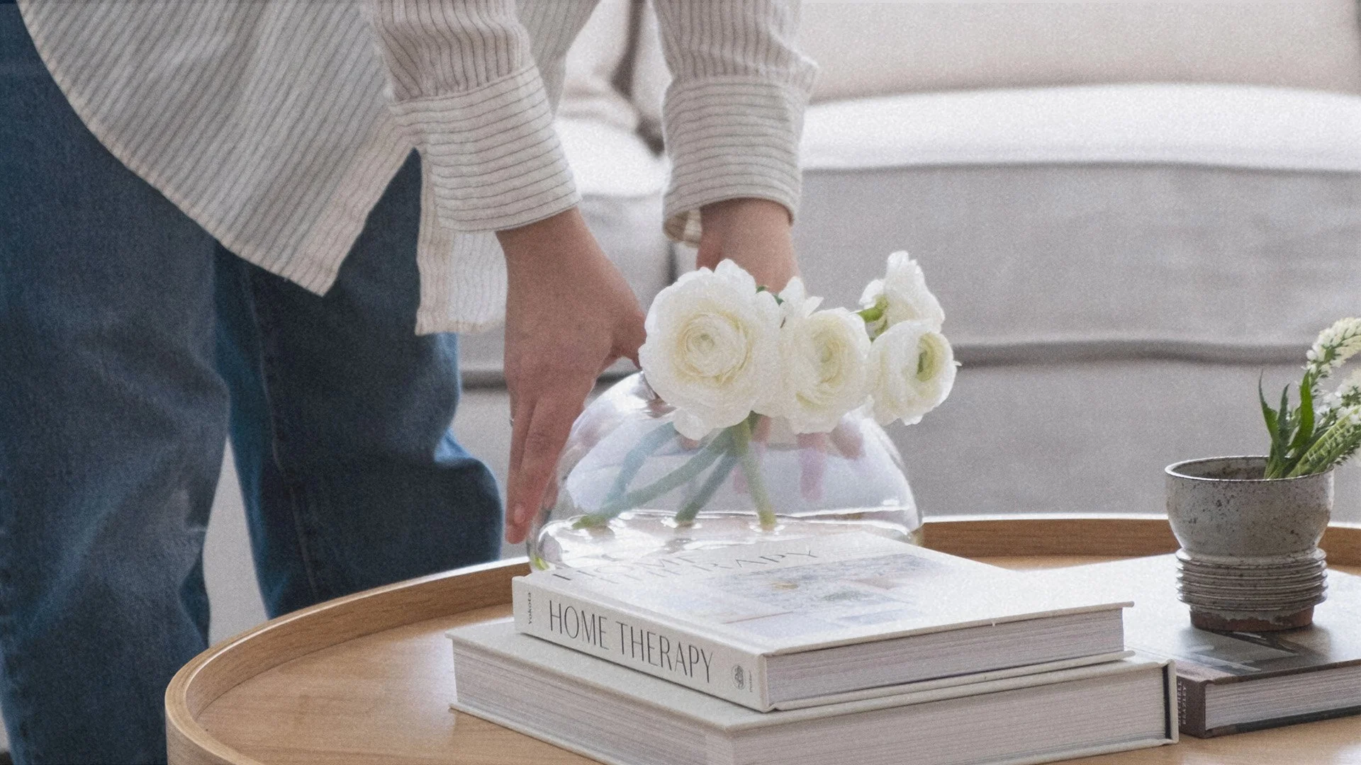 Mise en place d'un vase de fleurs blanches sur une table basse en bois, illustrant le stylisme d'intérieur soigné et l'ambiance apaisante des projets de Studio Lagom au Lac-Brome.