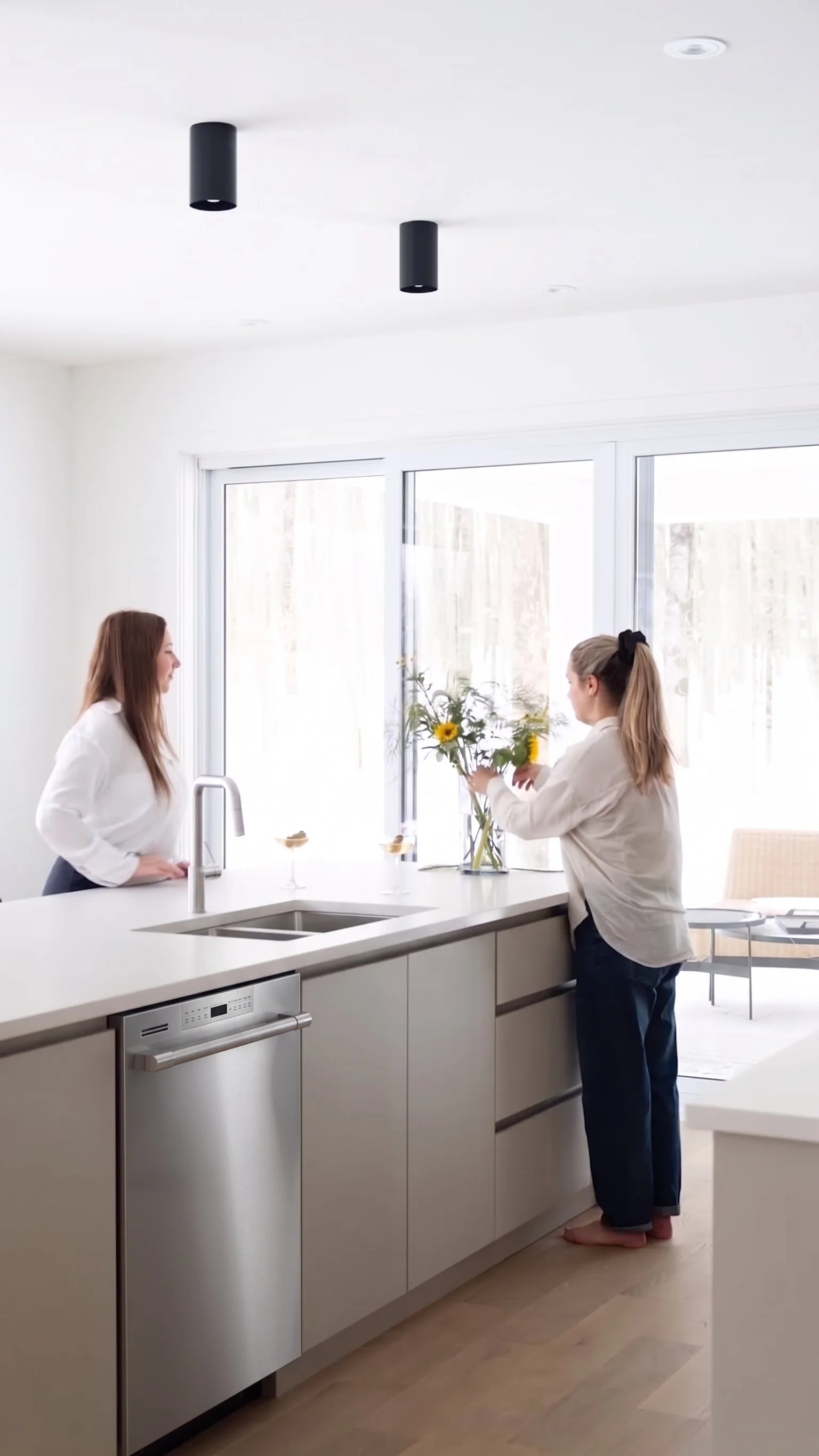 Aménagement d'une cuisine moderne et lumineuse avec îlot central greige, comptoir blanc, évier double.