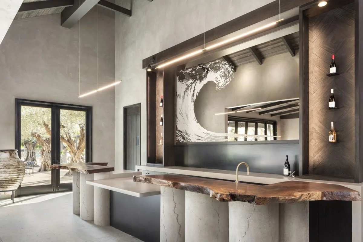 Modern kitchen with a live edge wood countertop, concrete cabinetry, and a large wave mural mirror.