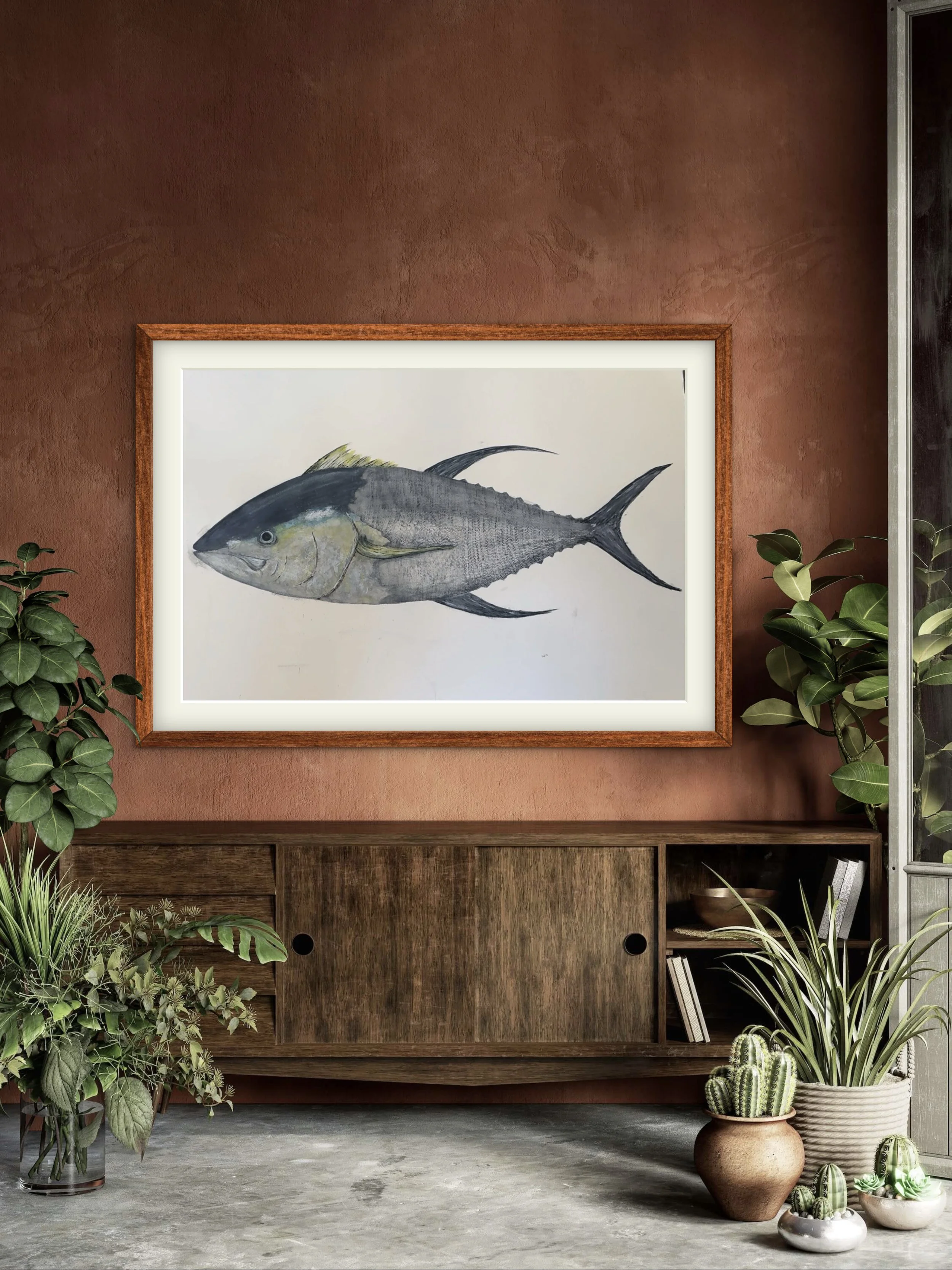 A framed watercolor painting or print of a fish hanging on a brown textured wall, surrounded by green houseplants in various pots on the floor.
