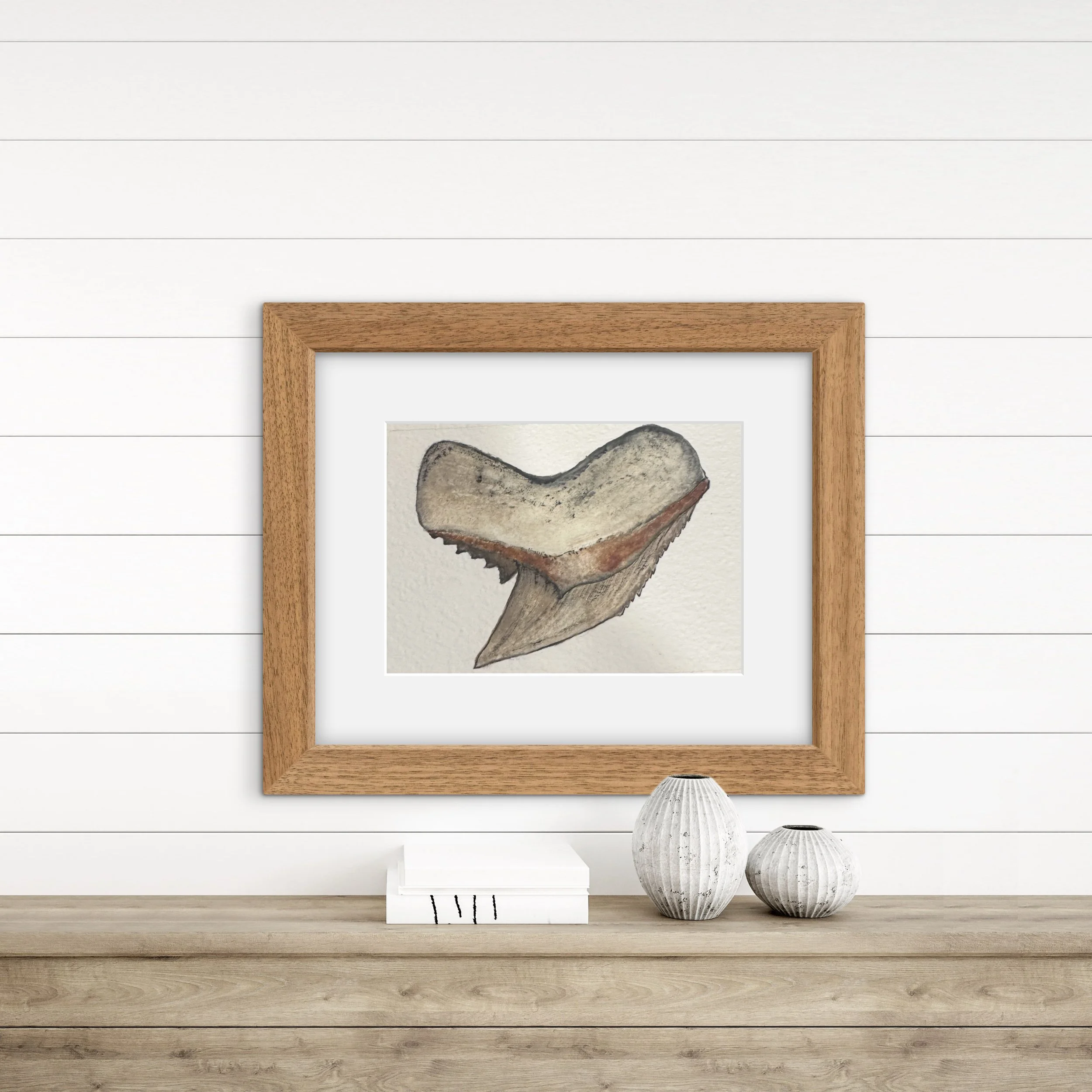 A wooden picture frame resting on a white shiplap wall, with two white ceramic vases with ridged textures on the floor in front of it.
