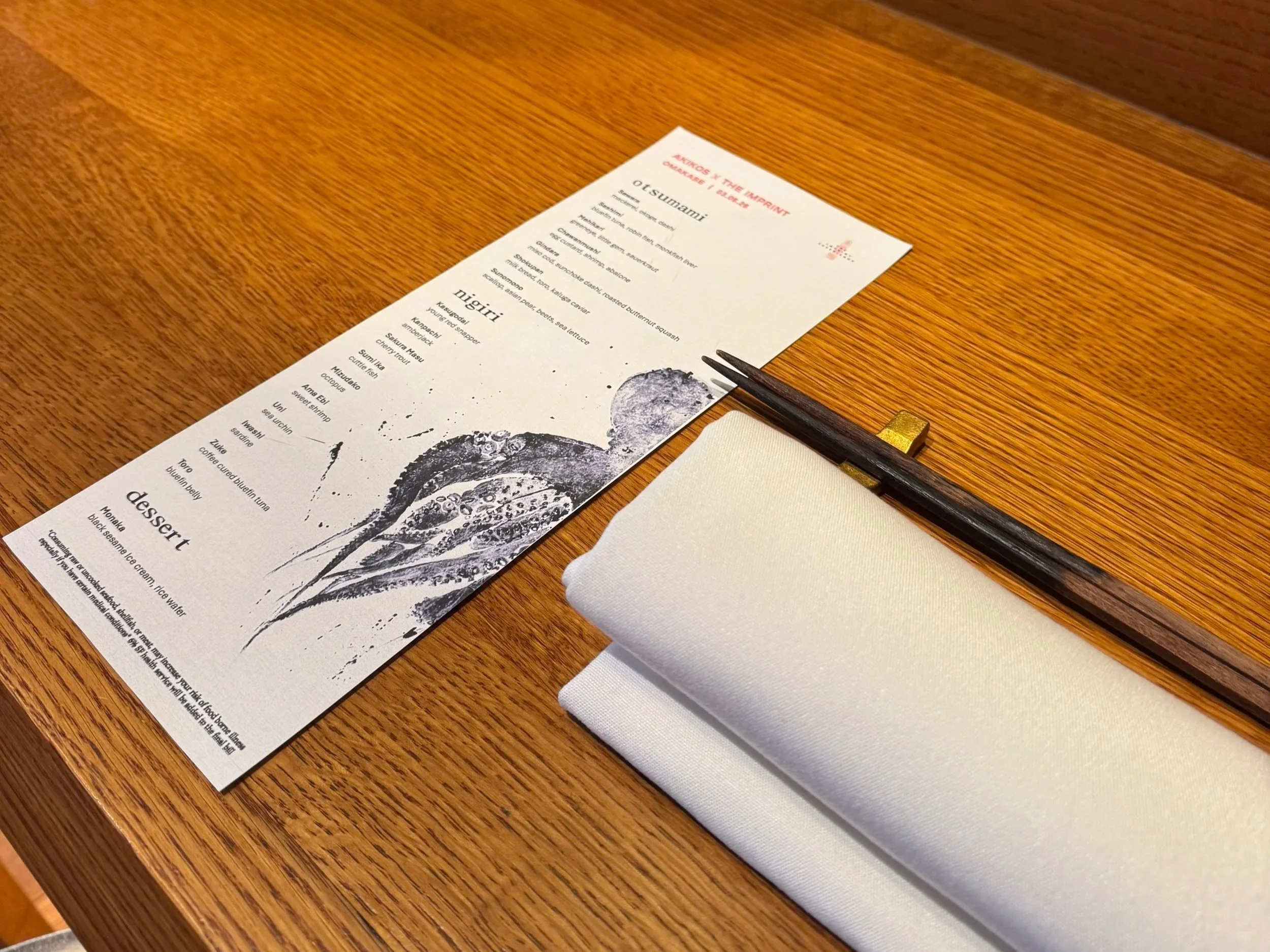 A restaurant menu on a wooden table, with chopsticks and a white napkin beside it.