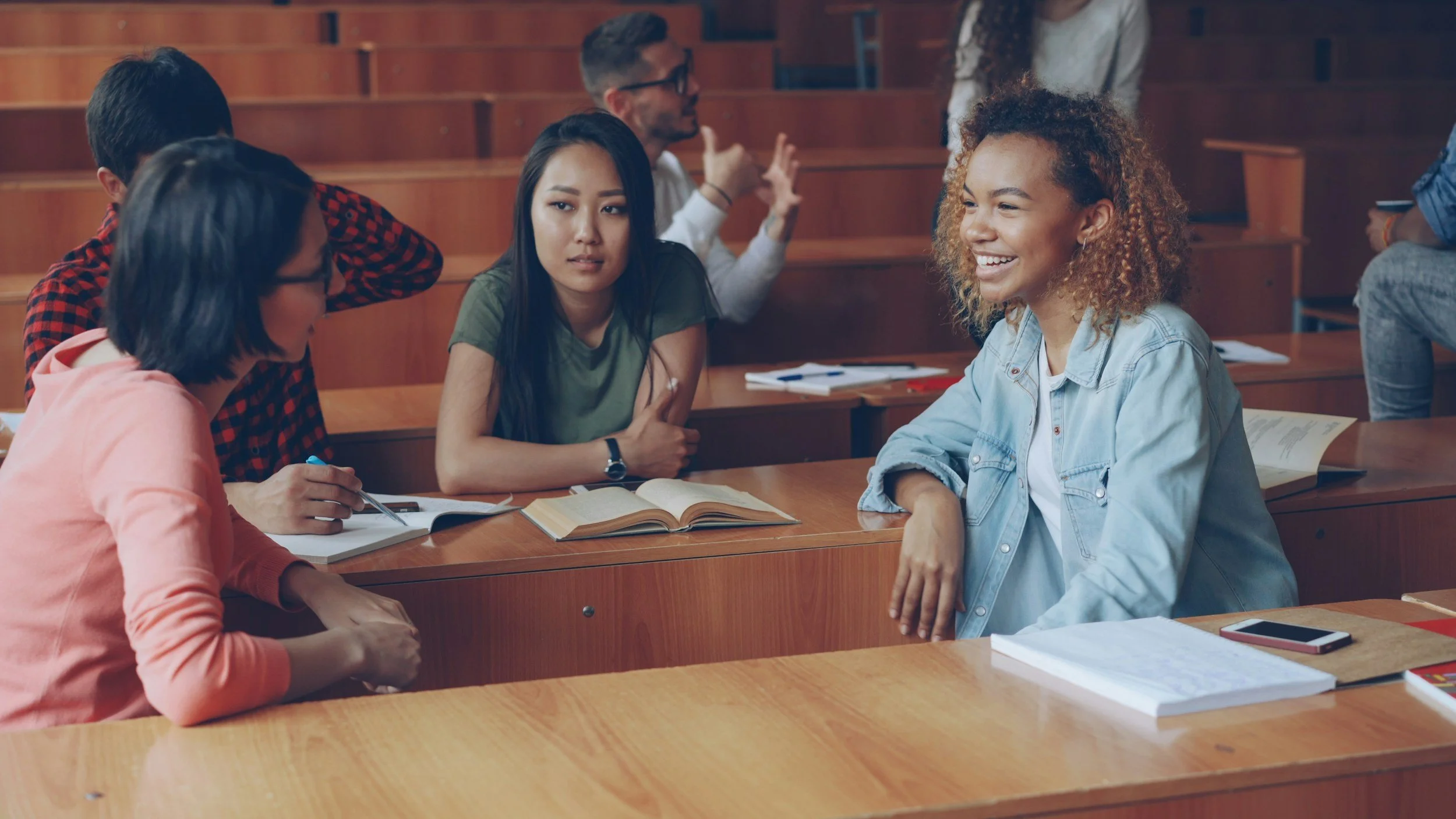 Thoughtful student with arms crossed sits beside smiling student with curly hair, engaged in Specialist High Skills Major certications in Ontario.