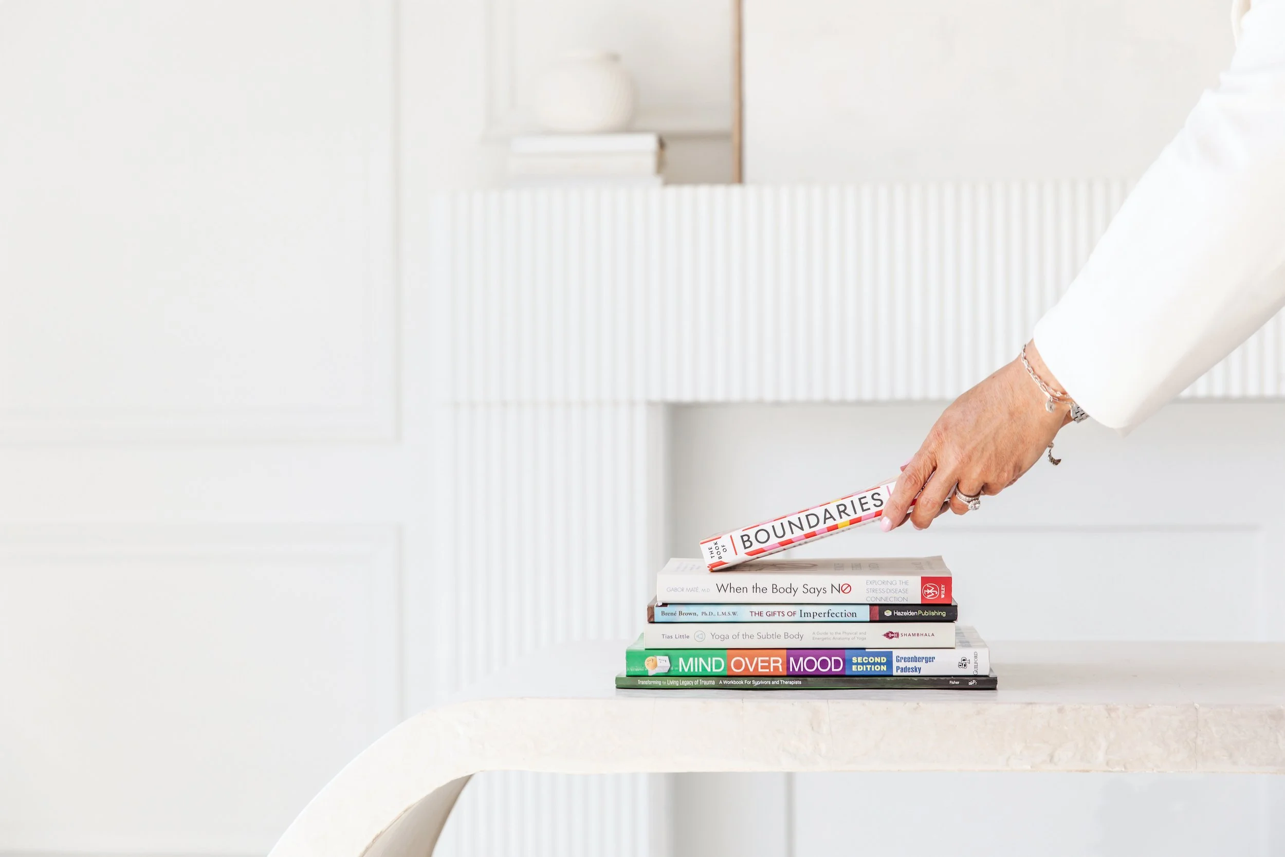 Close-up of therapy book stack with "Boundaries" prominently held by therapy provider Danielle Pomeroy from Four Rooms Wellness.