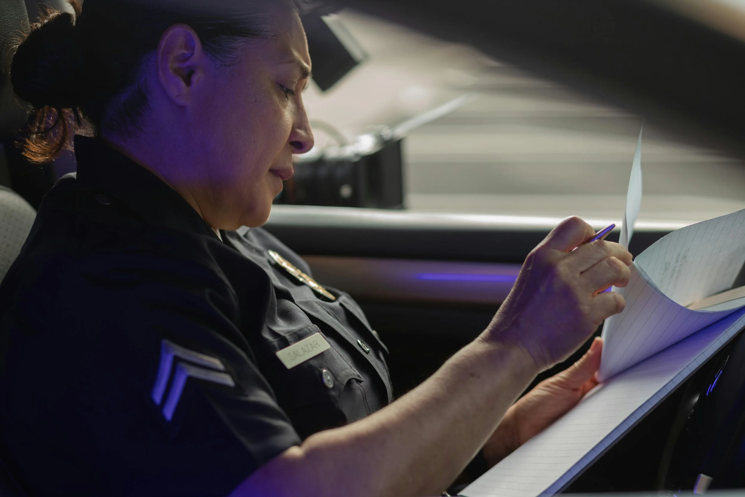 Female officer holding pen to paper in police car, depicting average first responder client for therapy sessions in Ontario. 