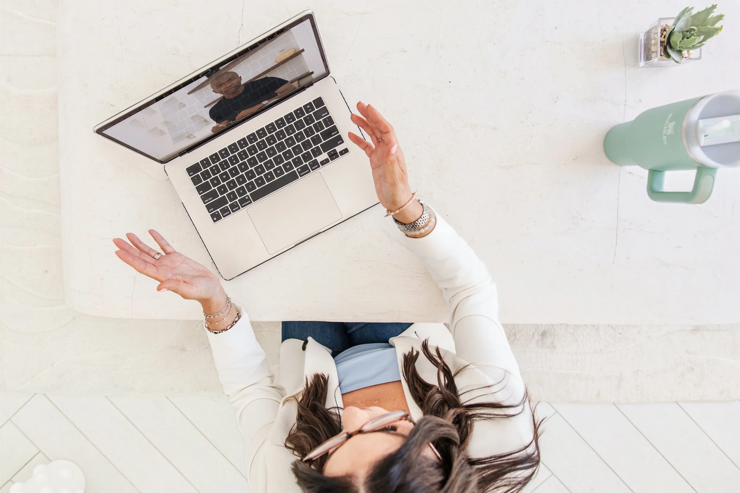 Top-down shot of participant in therapy sessions in Ontario, hands up during online video consultation on MacBook.