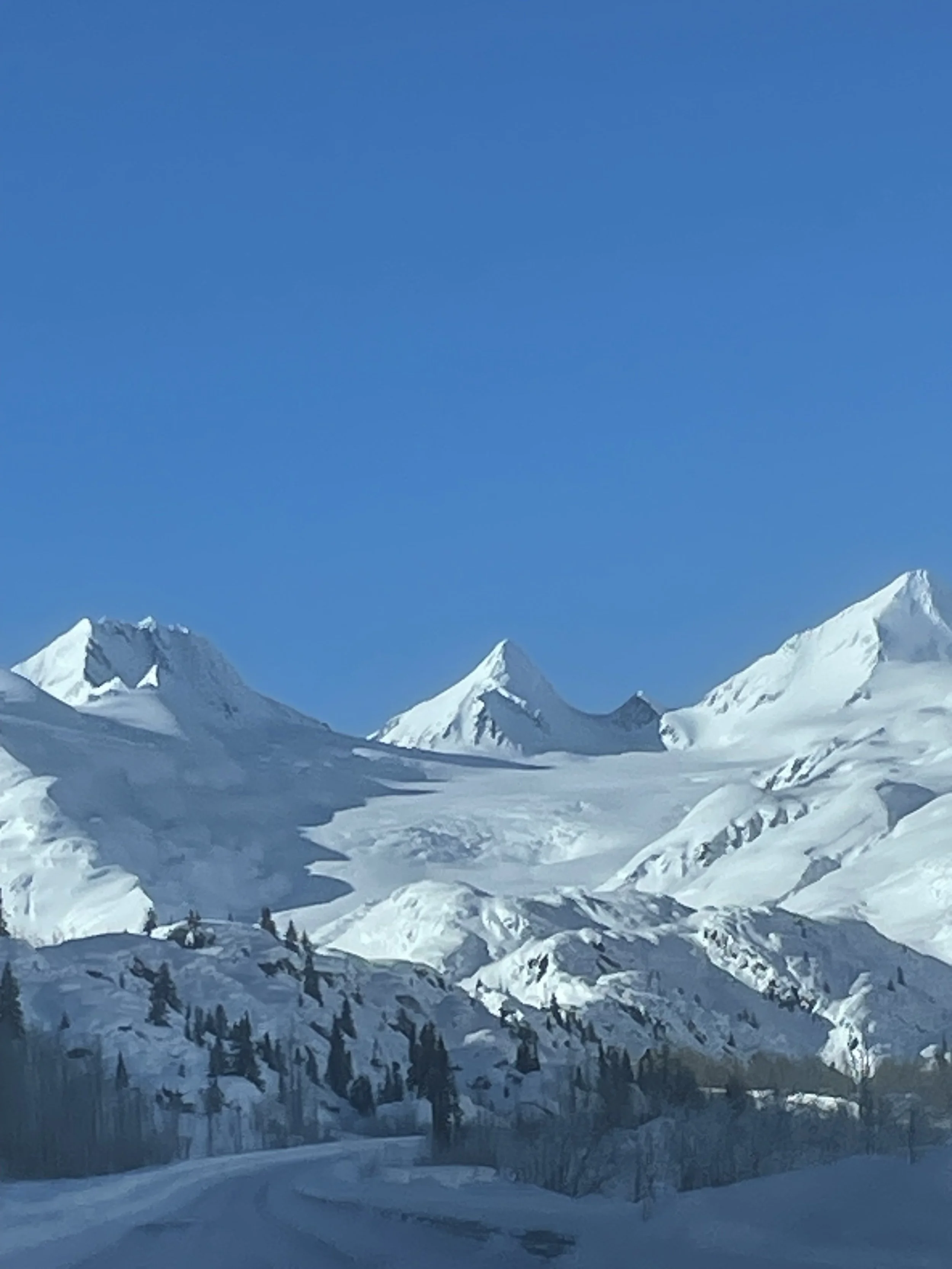 Snow-covered mountains under a clear blue sky with a snow-lined road in the foreground.