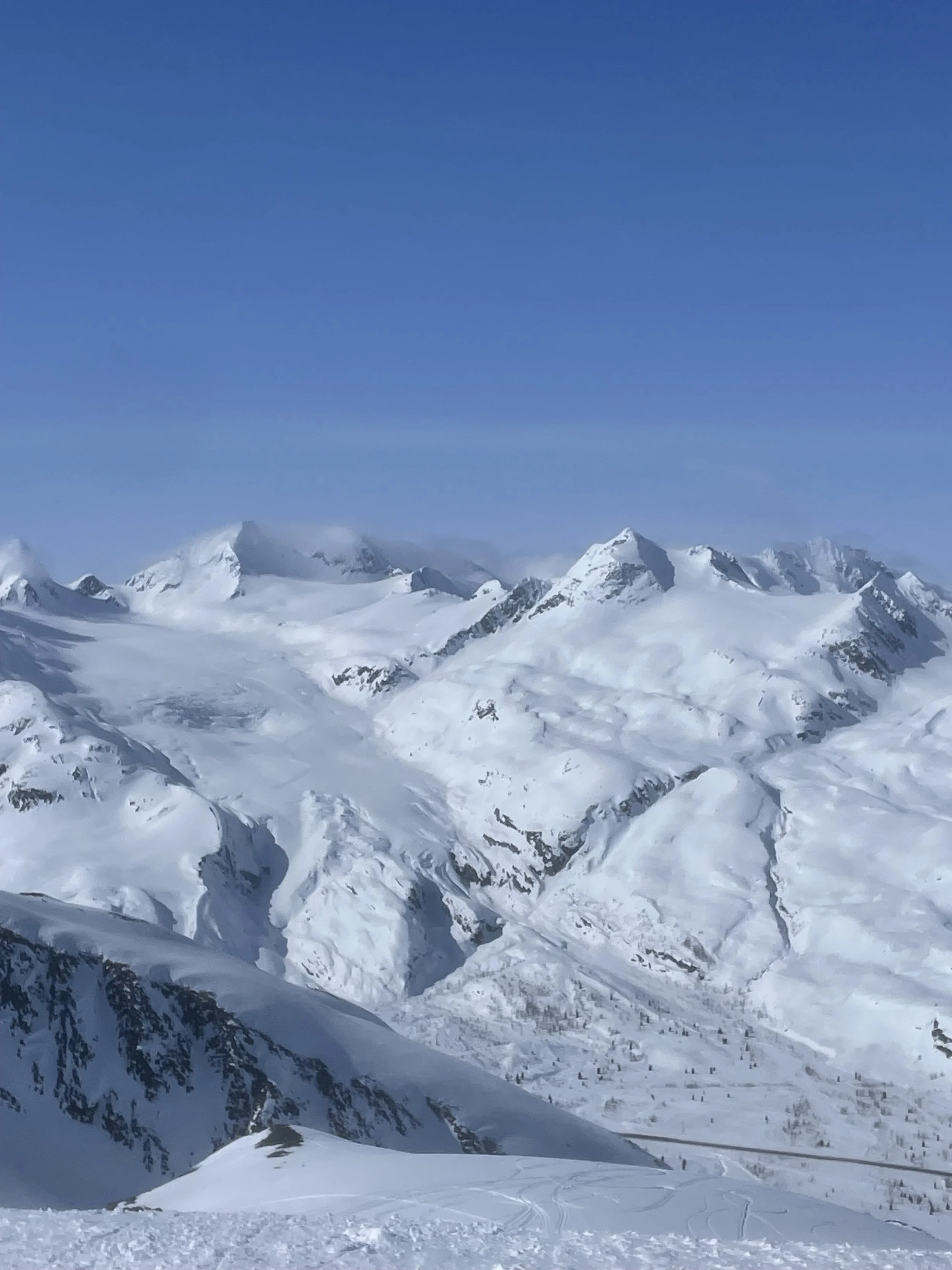 Snow-covered mountain range under clear blue sky.