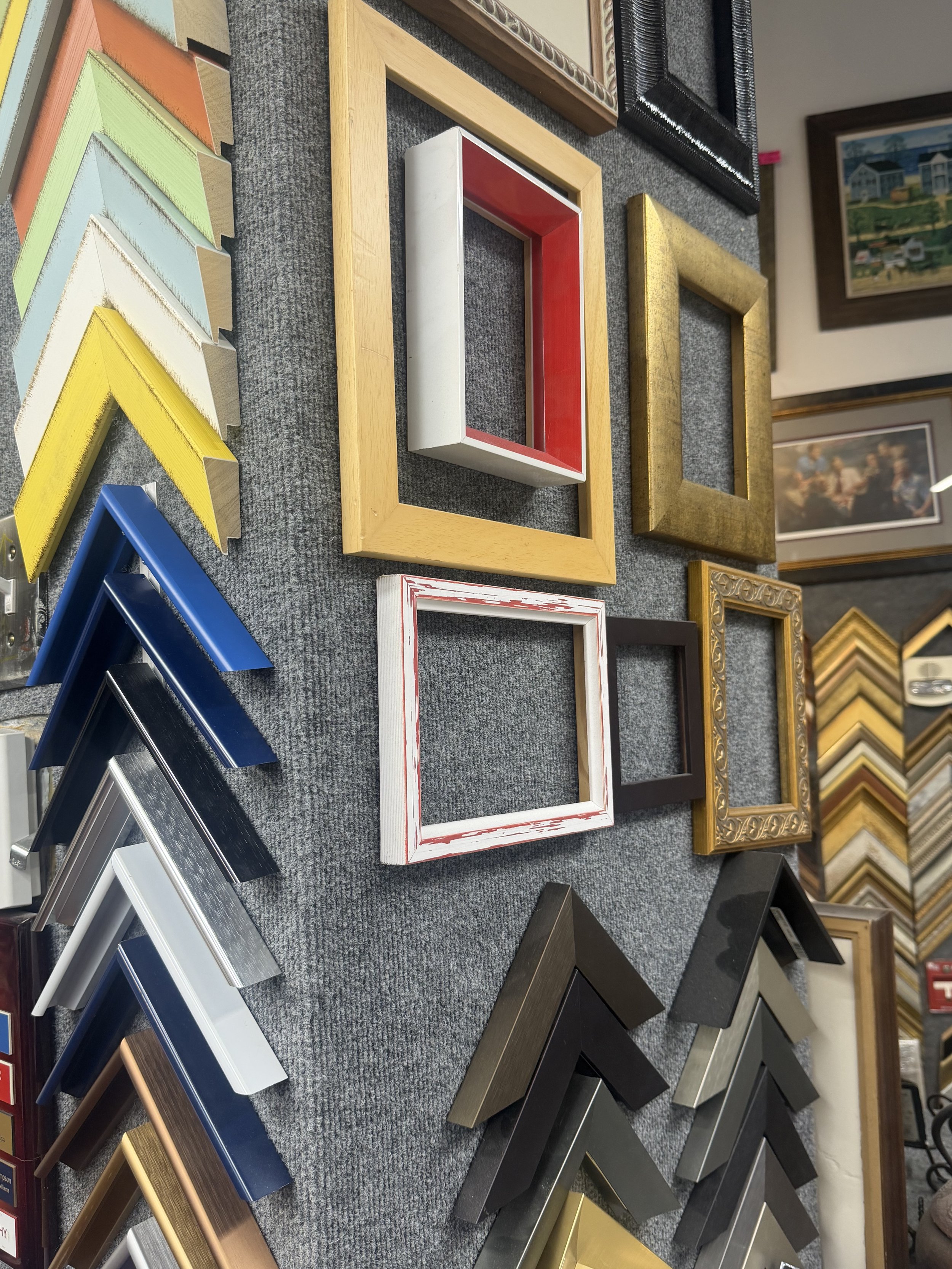 Display of various picture frame samples in different colors, styles, and finishes on a retail display table.