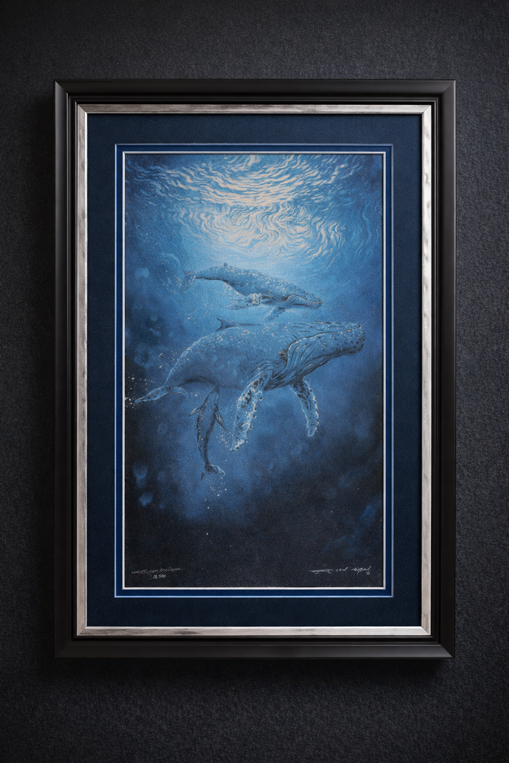 Framed artwork featuring underwater scene with whales and a swimmer, predominantly in blue tones.
