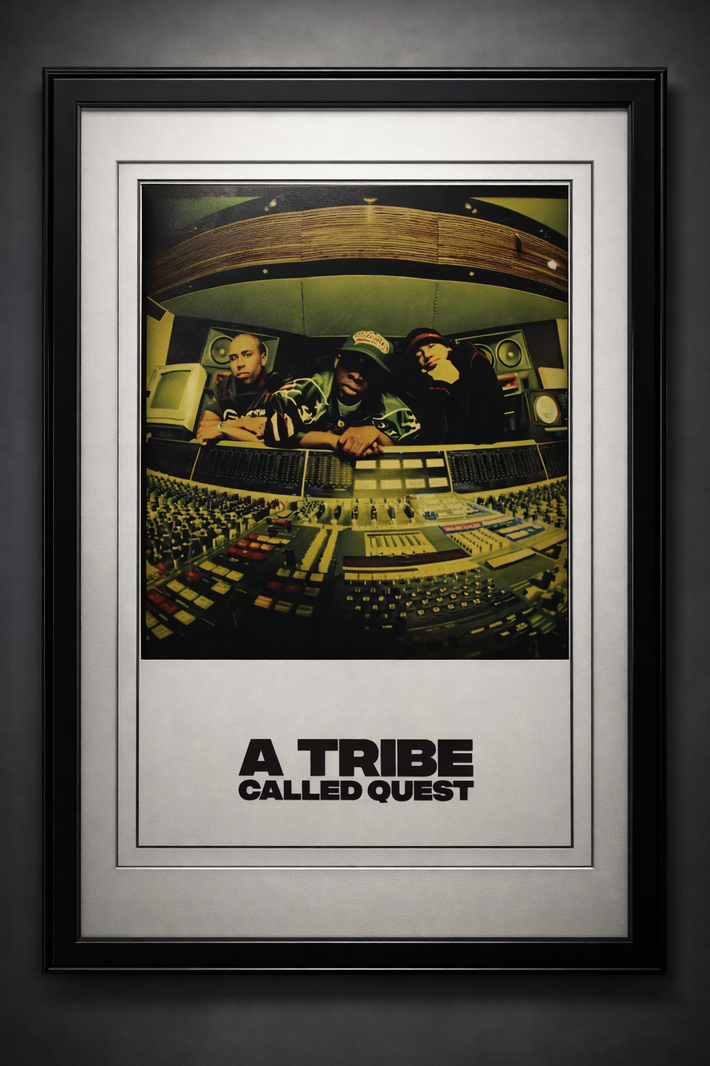 A framed poster of the music group A Tribe Called Quest, featuring three members in a studio with a mixing console.