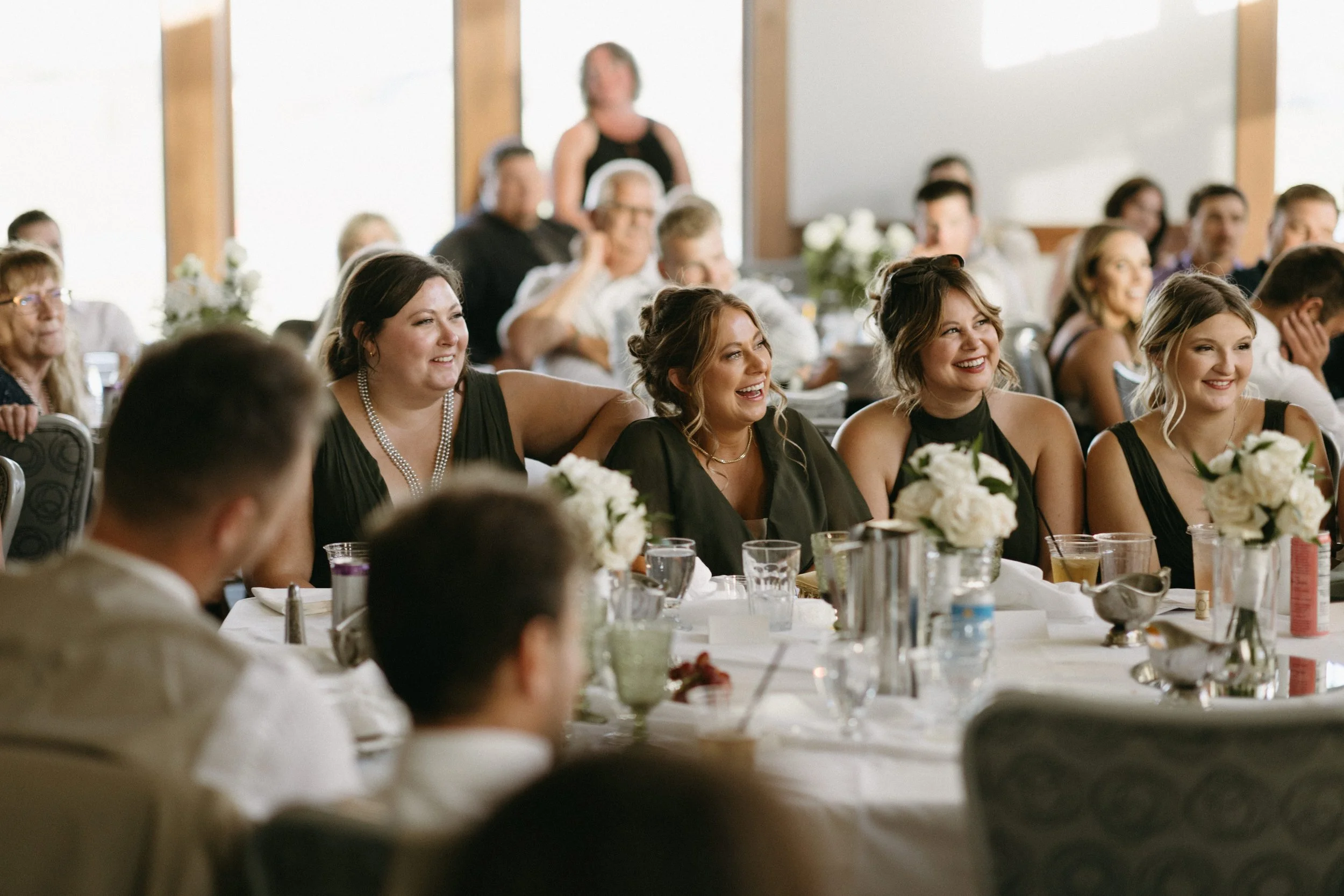 Guests seated at a table during a celebratory event, smiling and enjoying themselves.