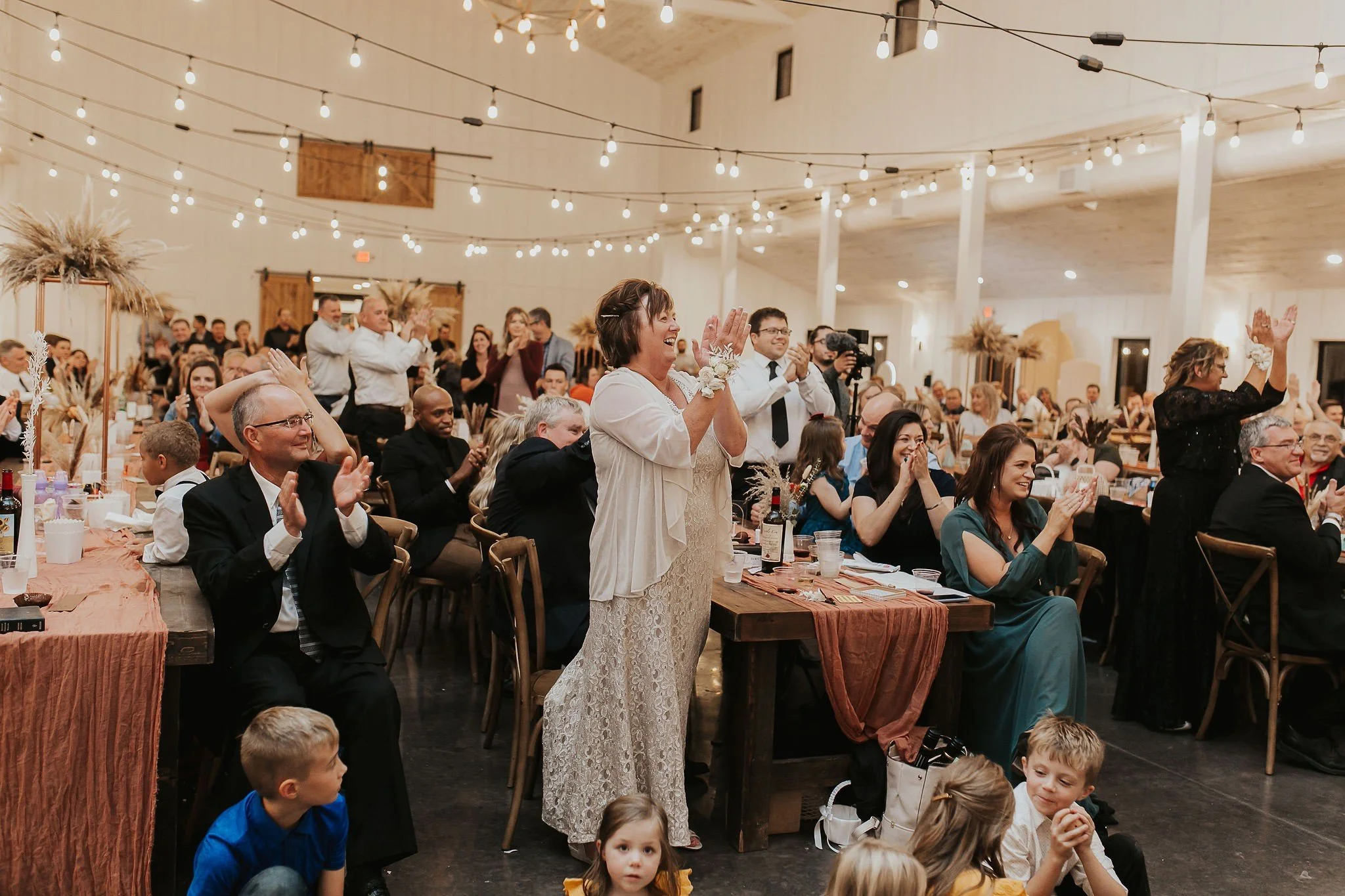 People applauding a best man speech decorated with string lights and rustic decor at The Pines, Davenport North Dakota .