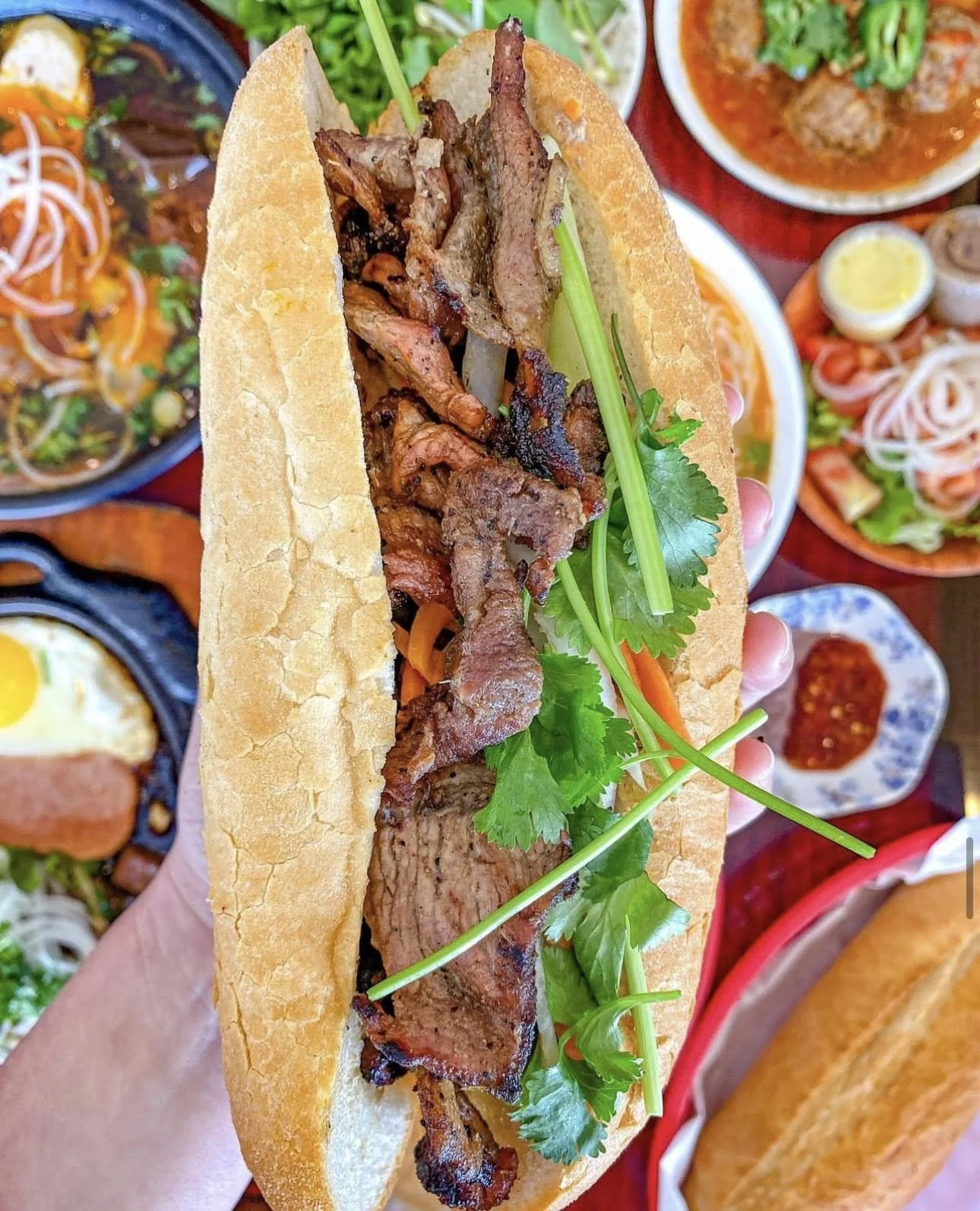 Vietnamese banh mi sandwich filled with grilled pork, beef, and fresh herbs.