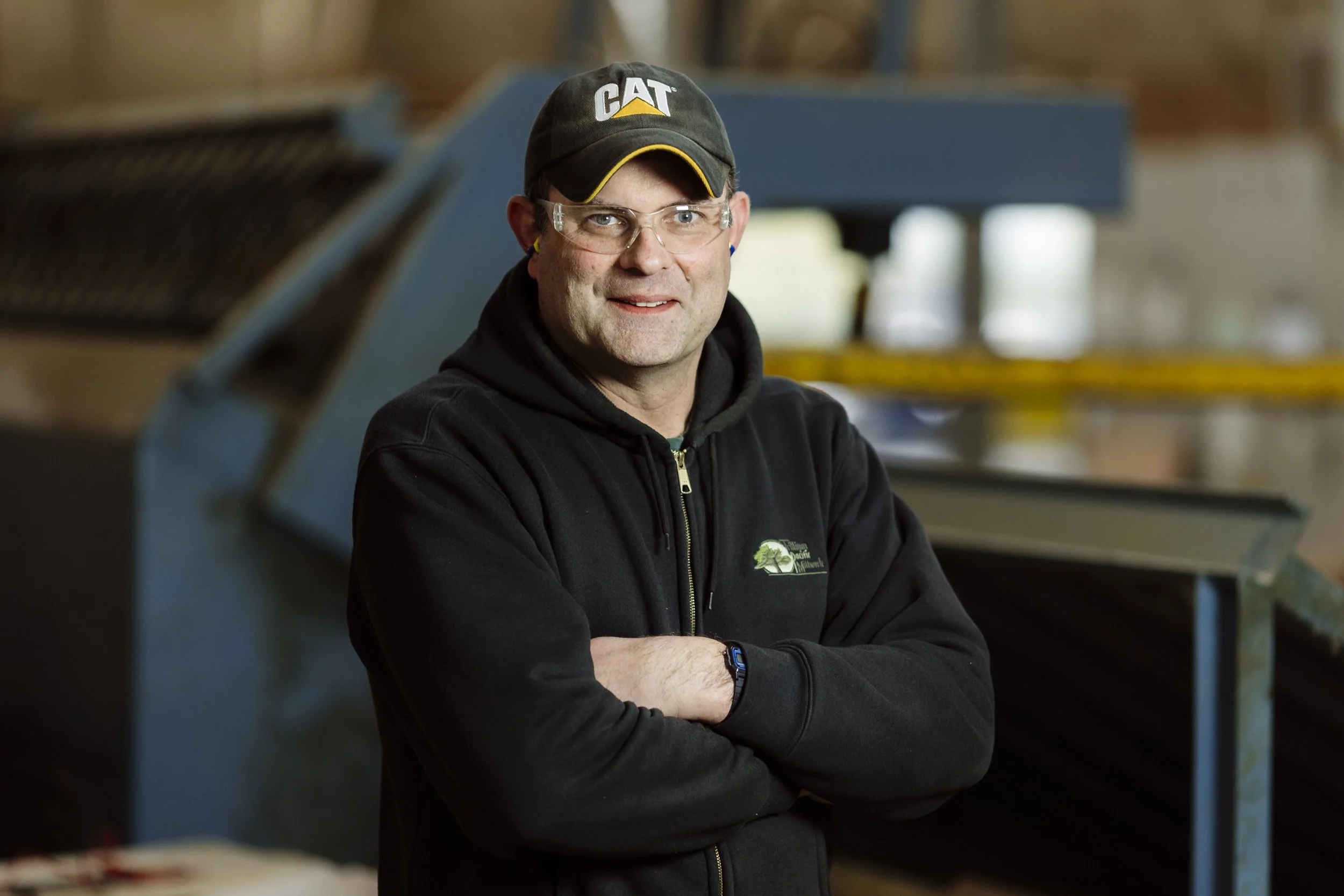 Young man standing with arms crossed in an industrial setting
