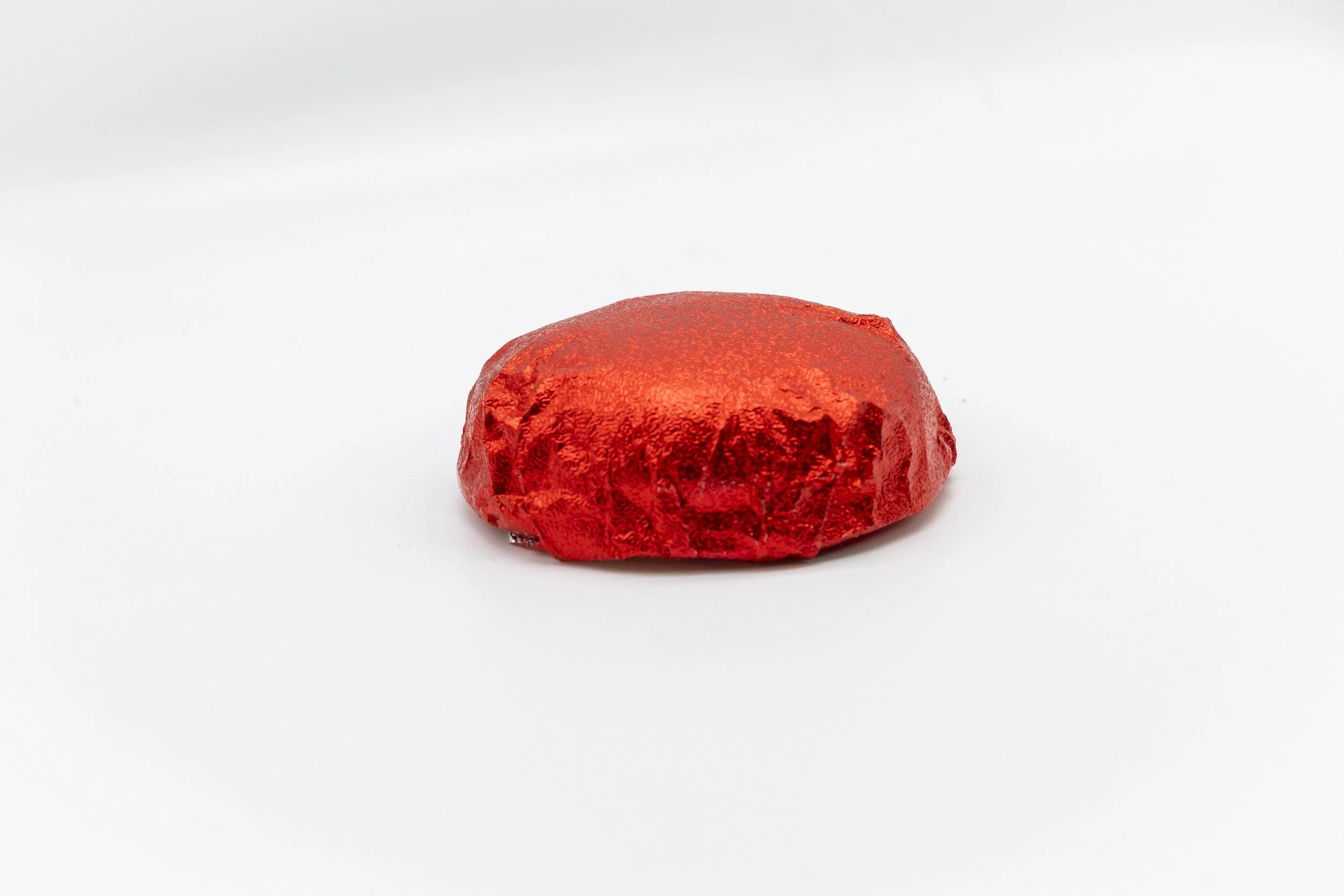 A round, red, foil-wrapped chocolate}