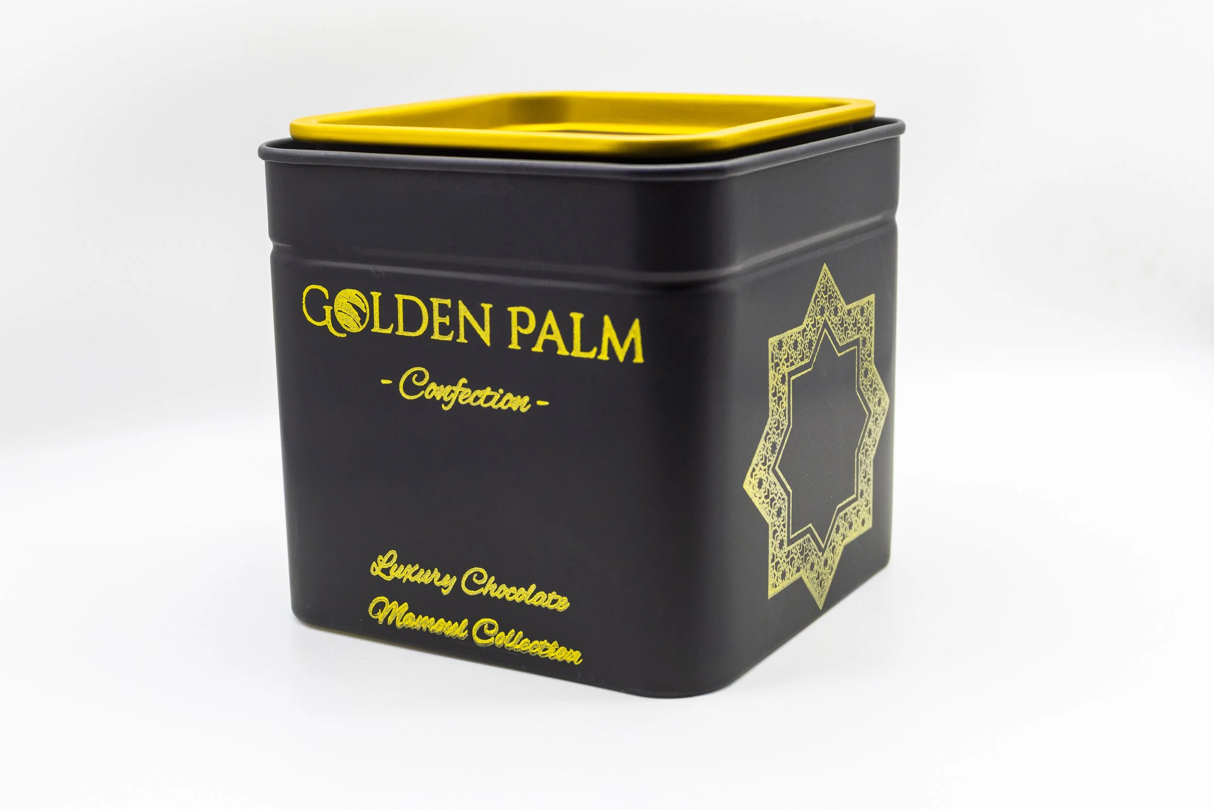 Black box with yellow lid and gold decoration labeled 'Golden Palm Confection' containing luxury chocolates from the Mamoul Collection.