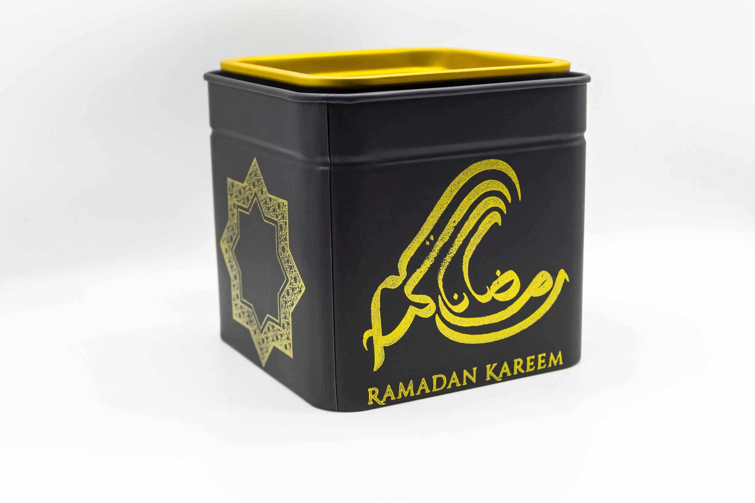 Black container with a yellow lid and yellow Arabic calligraphy with the words 'Ramadan Kareem' written in yellow.