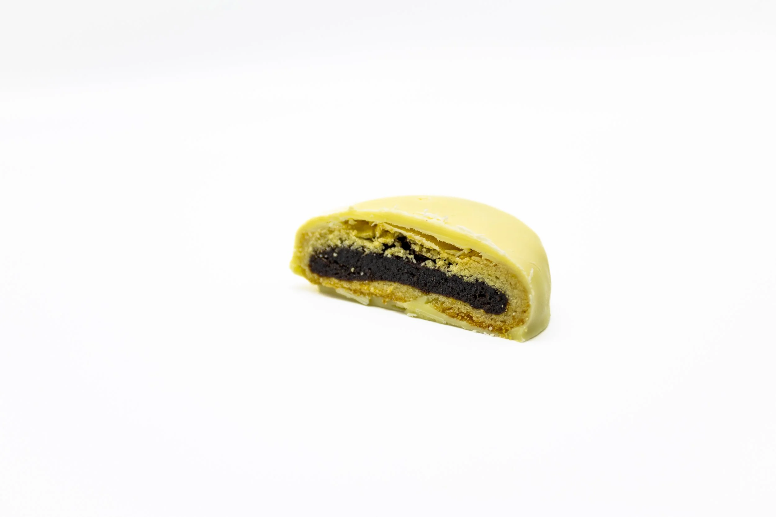 A cross-section of a white chocolate-covered éclair with a dark filling inside.