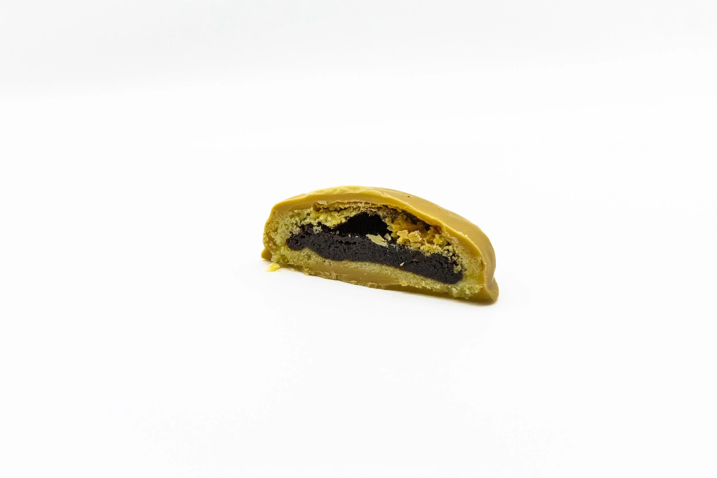A cross-section of a caramel chocolate coated mamoul on a white background.