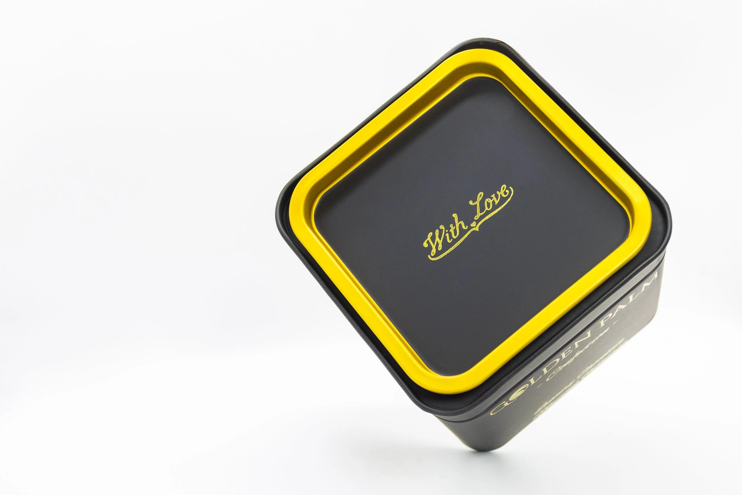 A black gift tin box with a golden rim, with the words 'With Love' written on top.