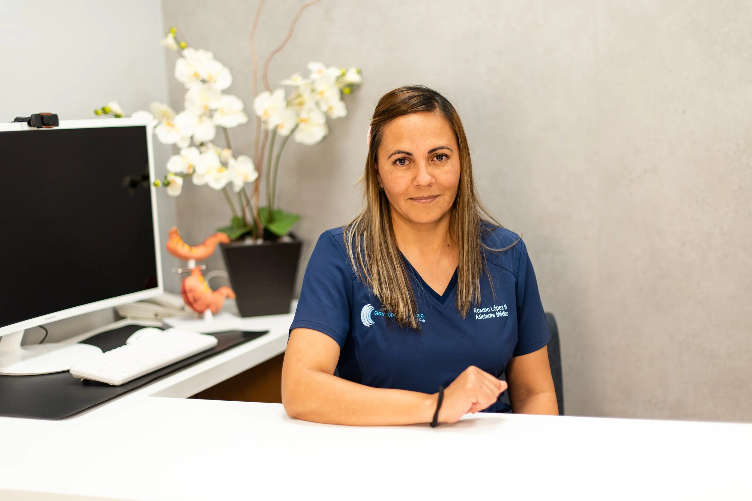Médico sentada en oficina con computadora y plantas en el fondo