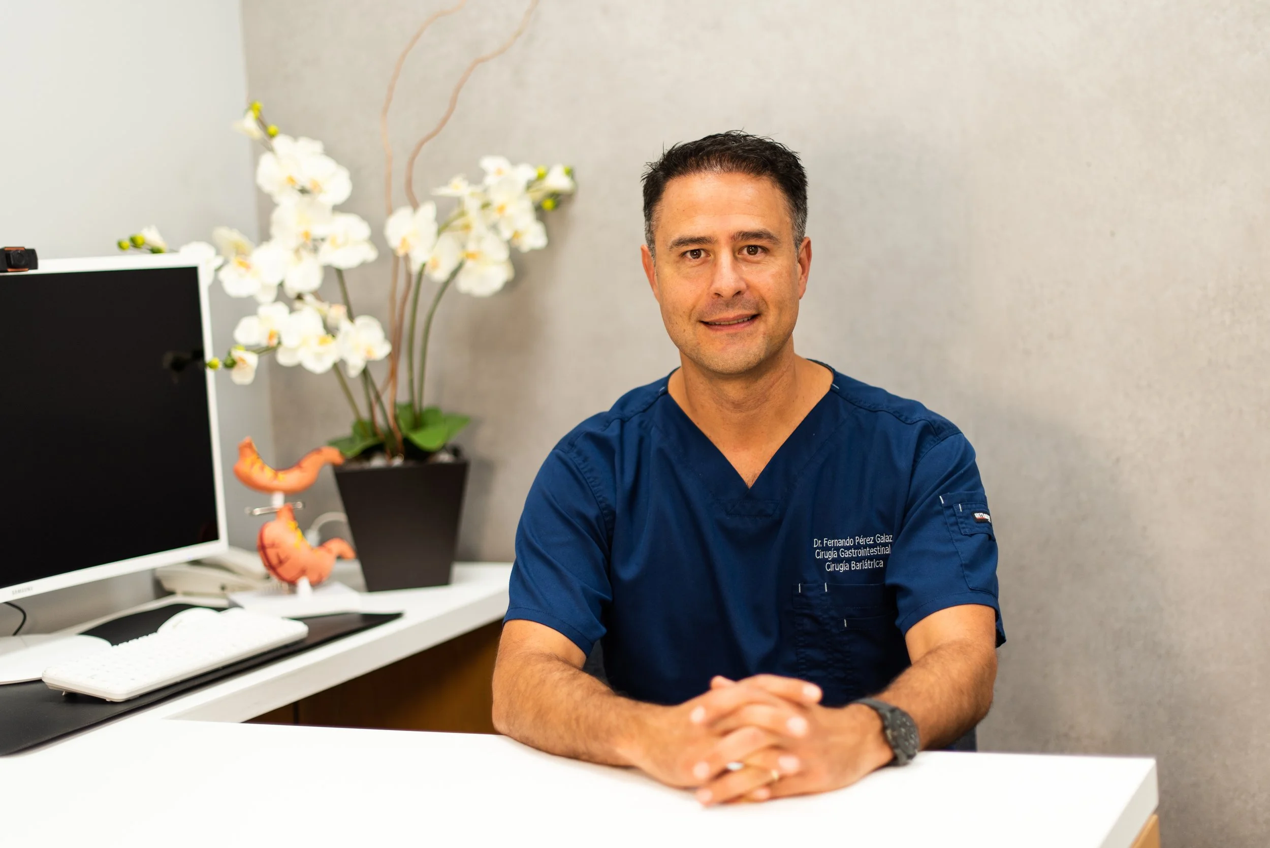 Hombre médico en consulta en oficina con decoraciones de flores y modelos anatómicos